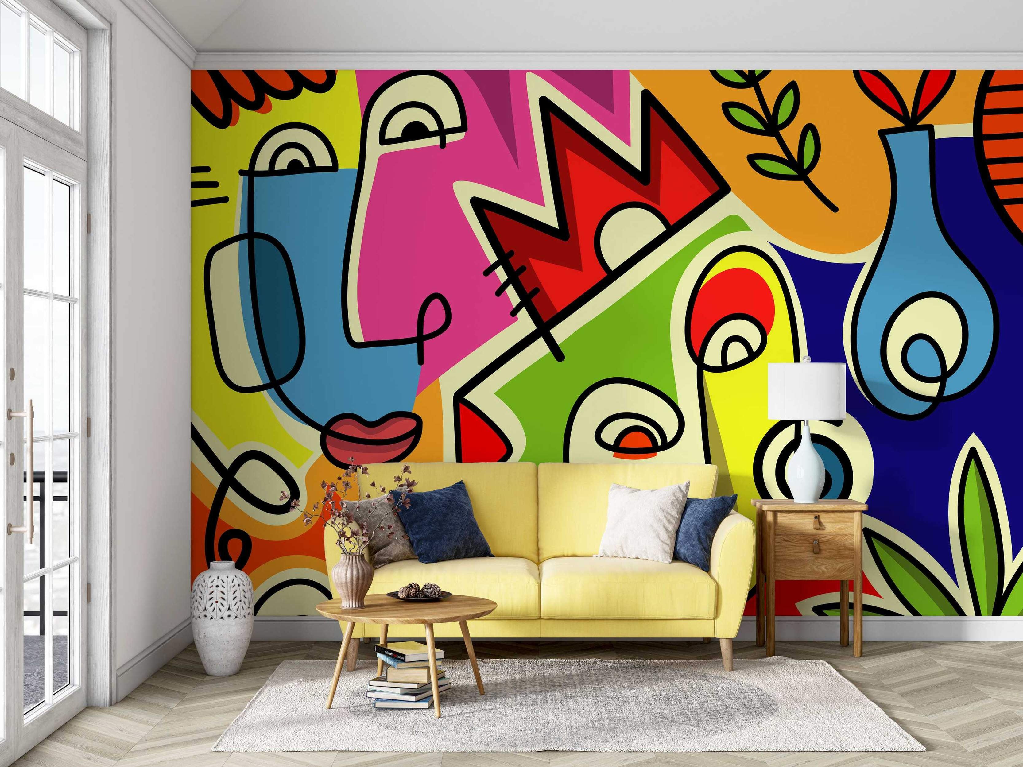 Colorful mural depicting abstract faces in a cubist style, using bold black lines and bright blocks of yellow, pink, blue, and green.