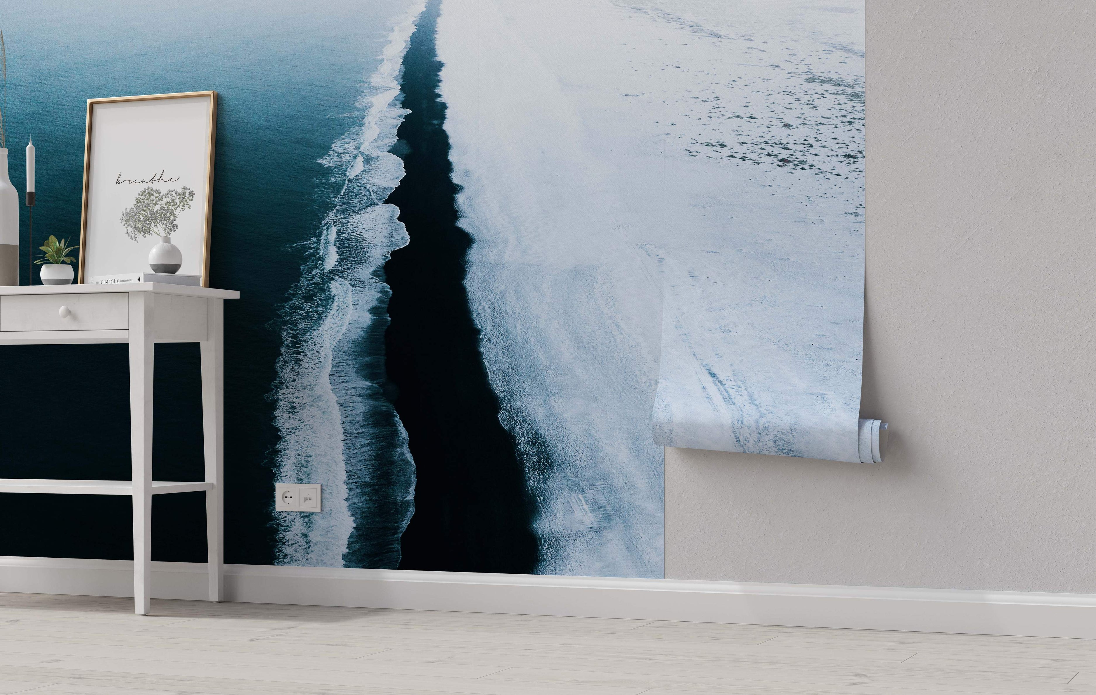 Aerial view mural showing deep blue ocean water with white foamy waves crashing onto a dark, contrasting sandy beach.