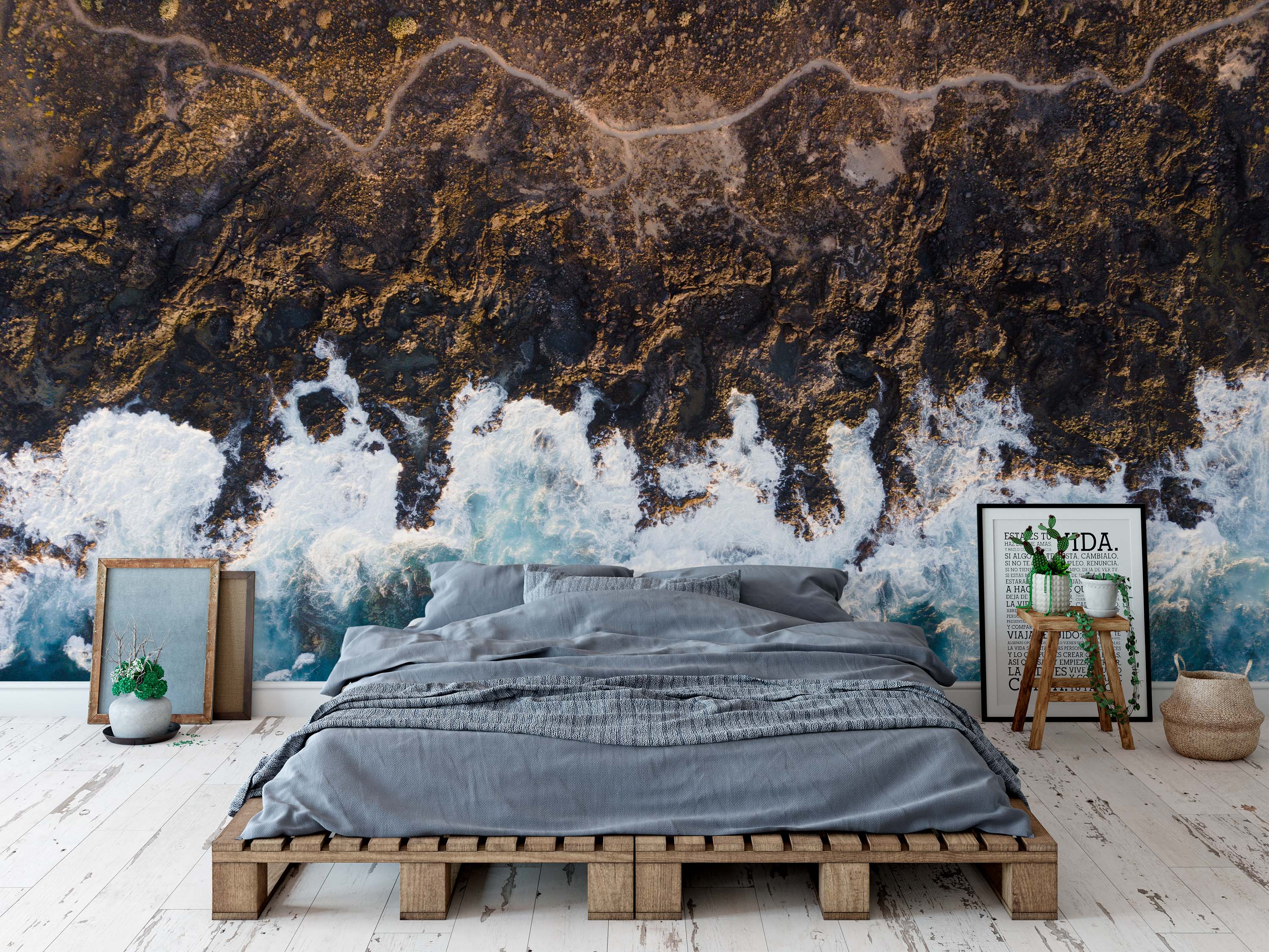 An aerial view mural of a rugged, dark rocky coastline with a winding path, contrasted by crashing white and blue ocean waves.