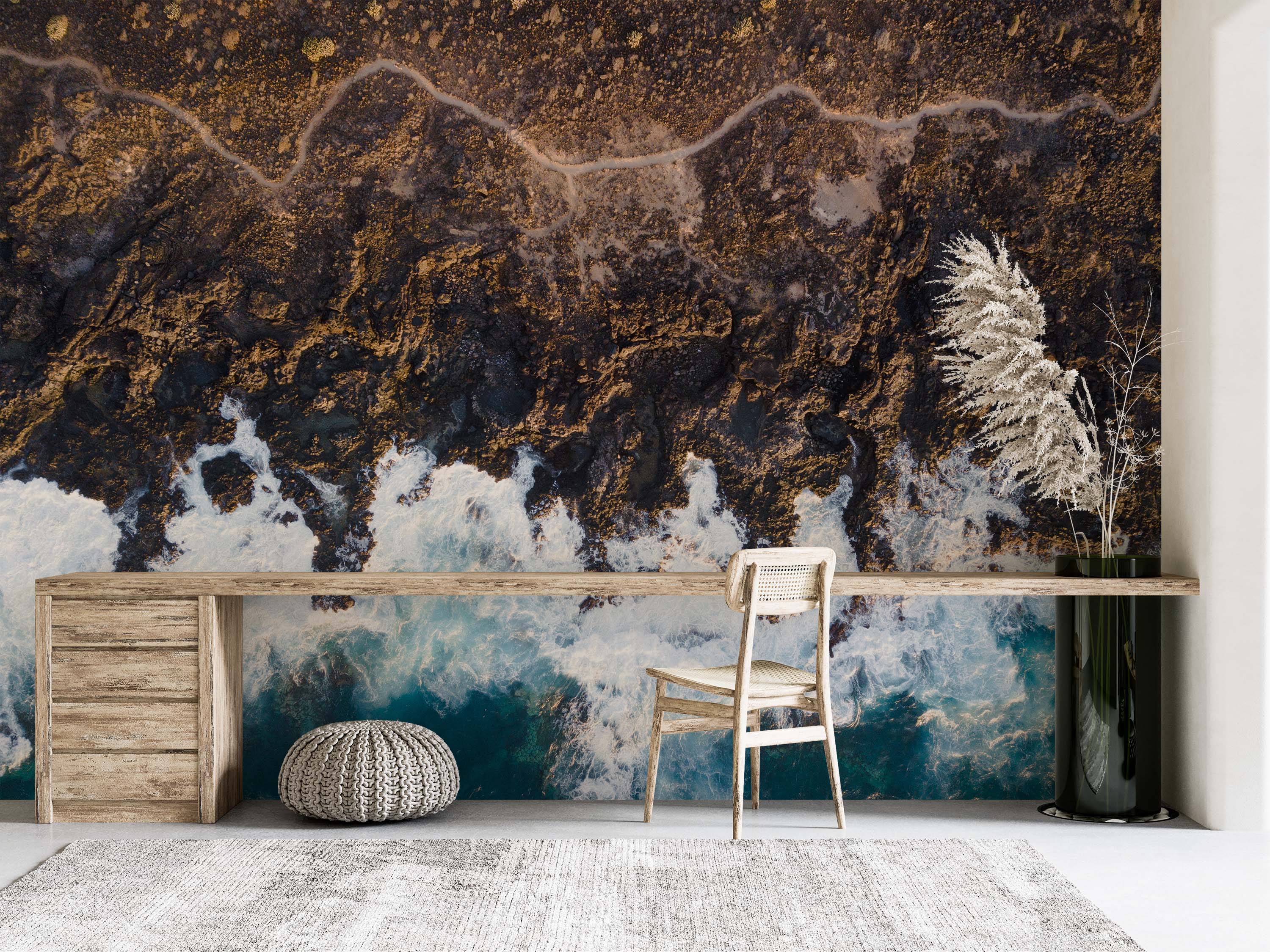 Mural depicting a dramatic aerial view of a rocky coastline in shades of brown and gold, meeting turbulent blue and white waves.