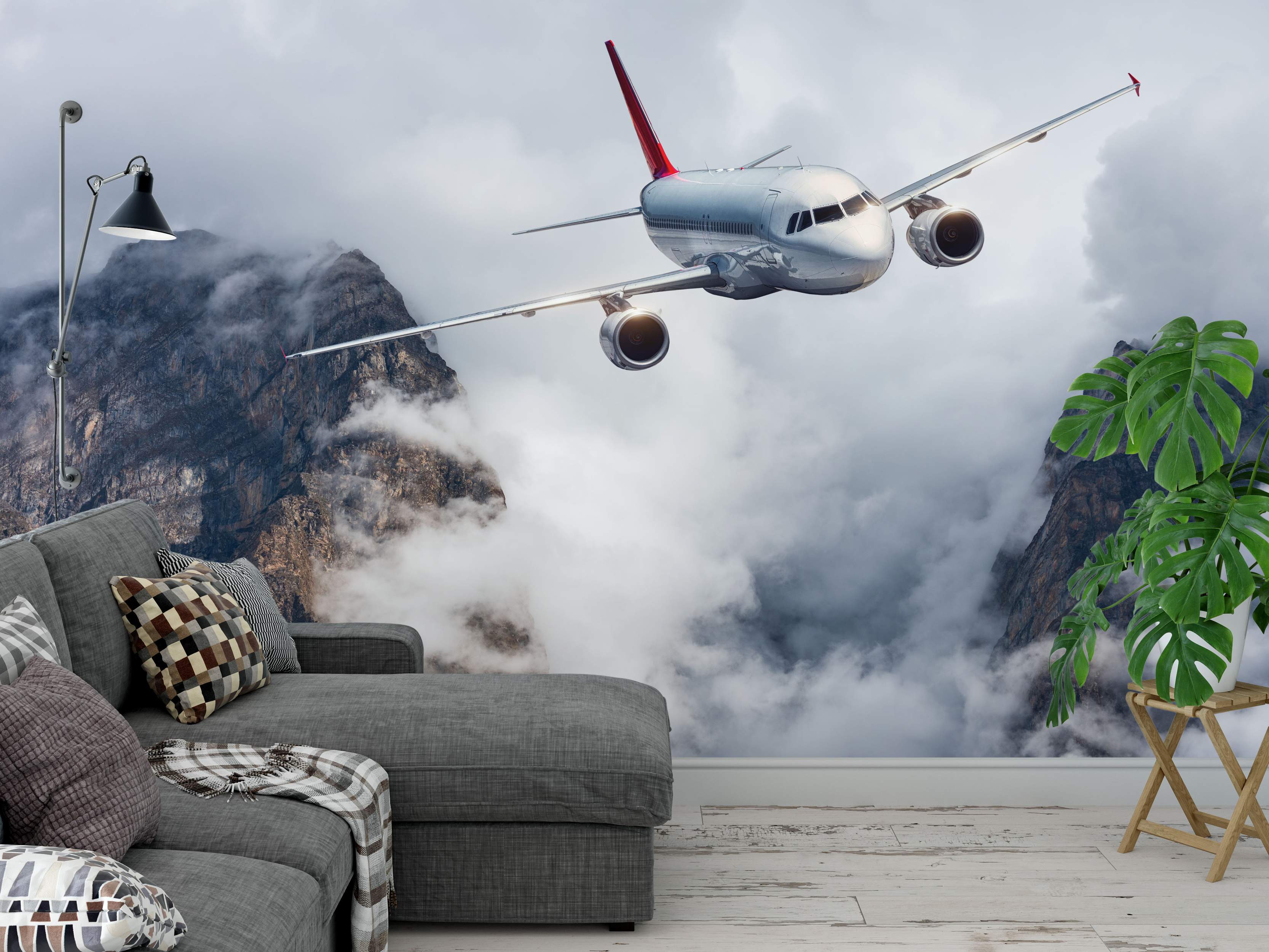 Photorealistic mural of a silver airplane with a red tail flying low through dramatic gray clouds between rocky mountains.