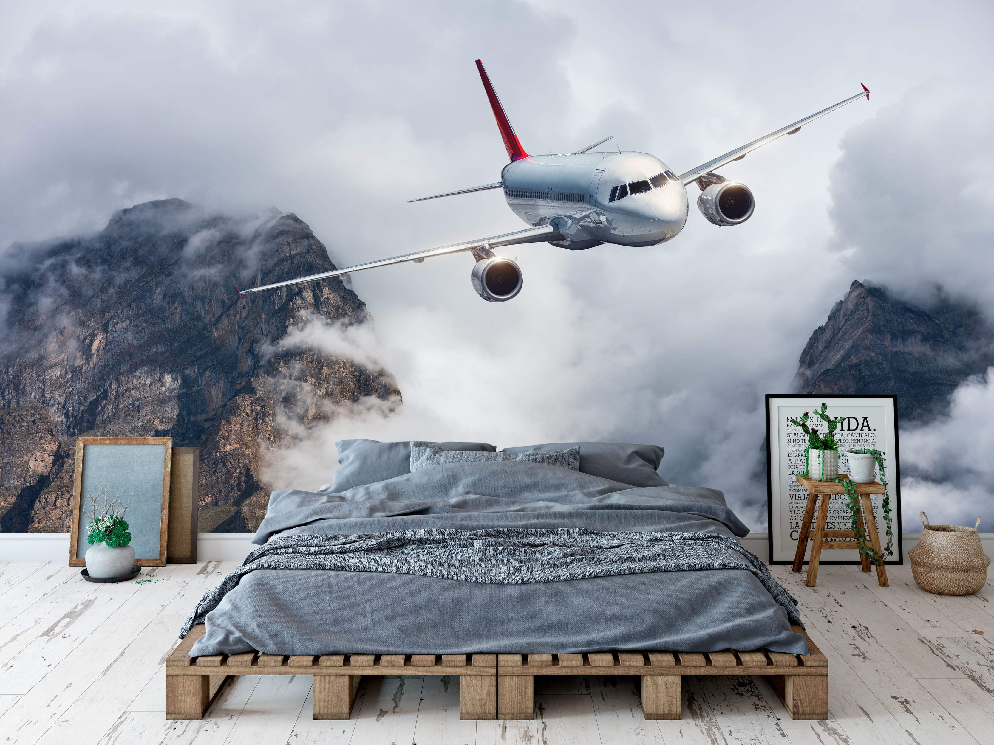 Photorealistic mural depicting a silver airplane with a red tail flying through grey clouds between rocky mountain peaks.