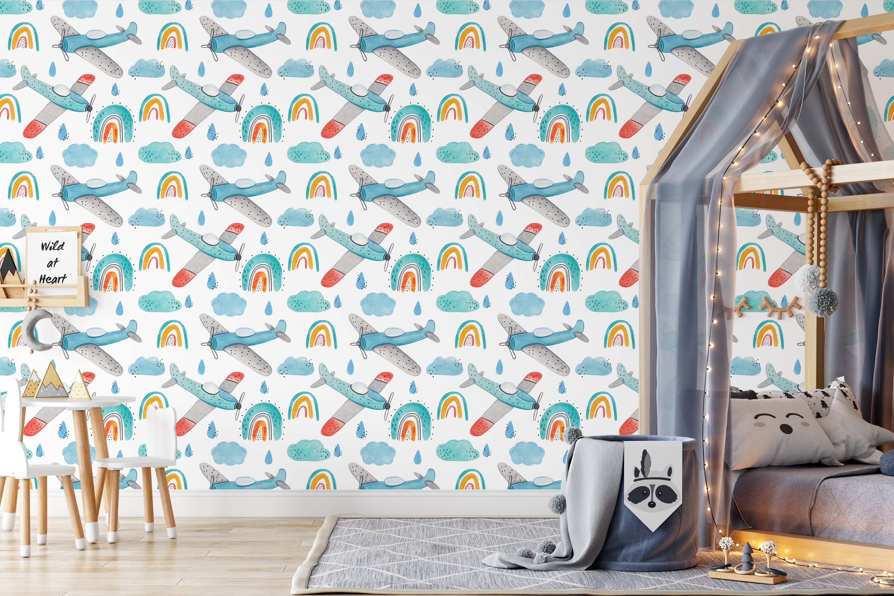 Whimsical wallpaper with a pattern of hand-drawn blue and gray airplanes, colorful rainbows, teal clouds, and blue raindrops on white.