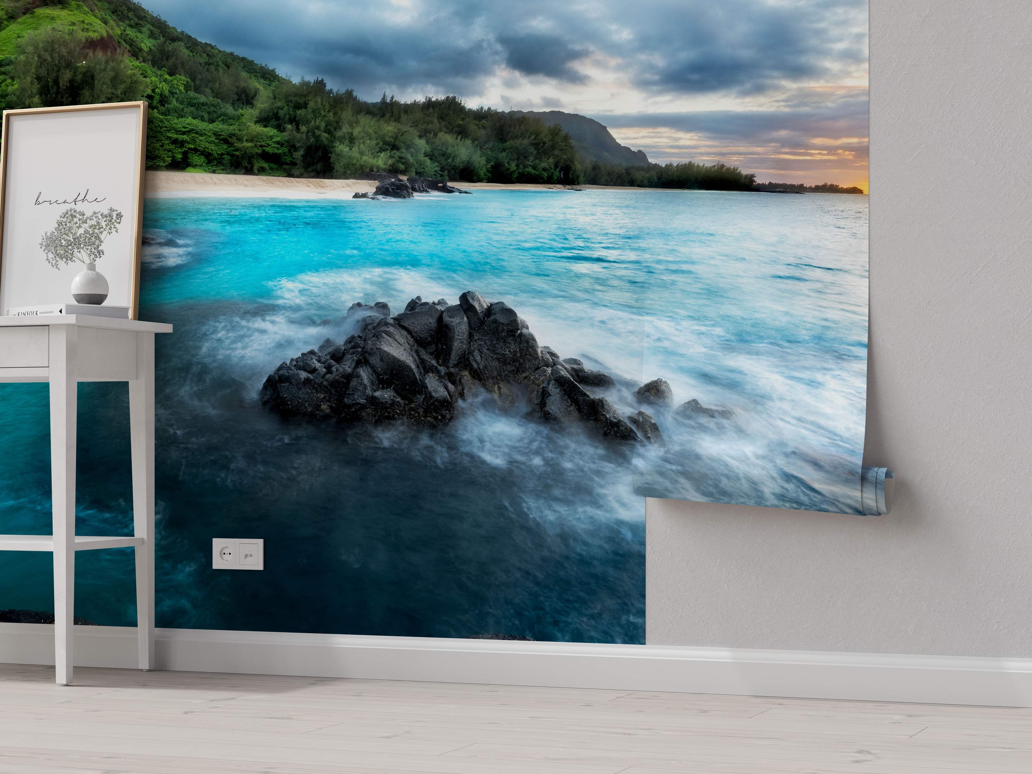 Photorealistic mural of a beach scene with turbulent blue ocean waves crashing on dark rocks, sandy shore, and green hills under a cloudy sky.