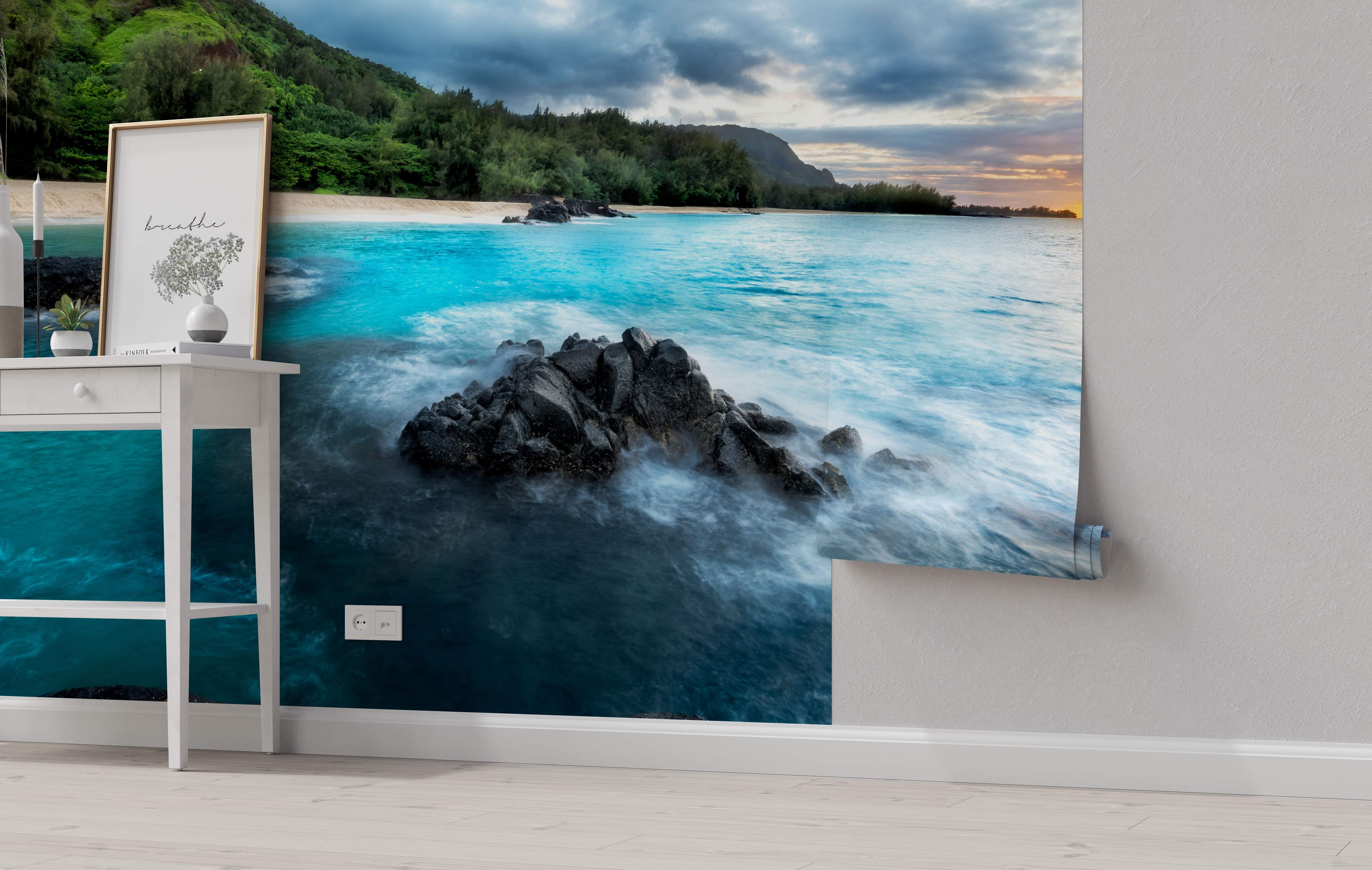 Photorealistic mural of a beach scene with turbulent blue ocean waves crashing on dark rocks, sandy shore, and green hills under a cloudy sky.