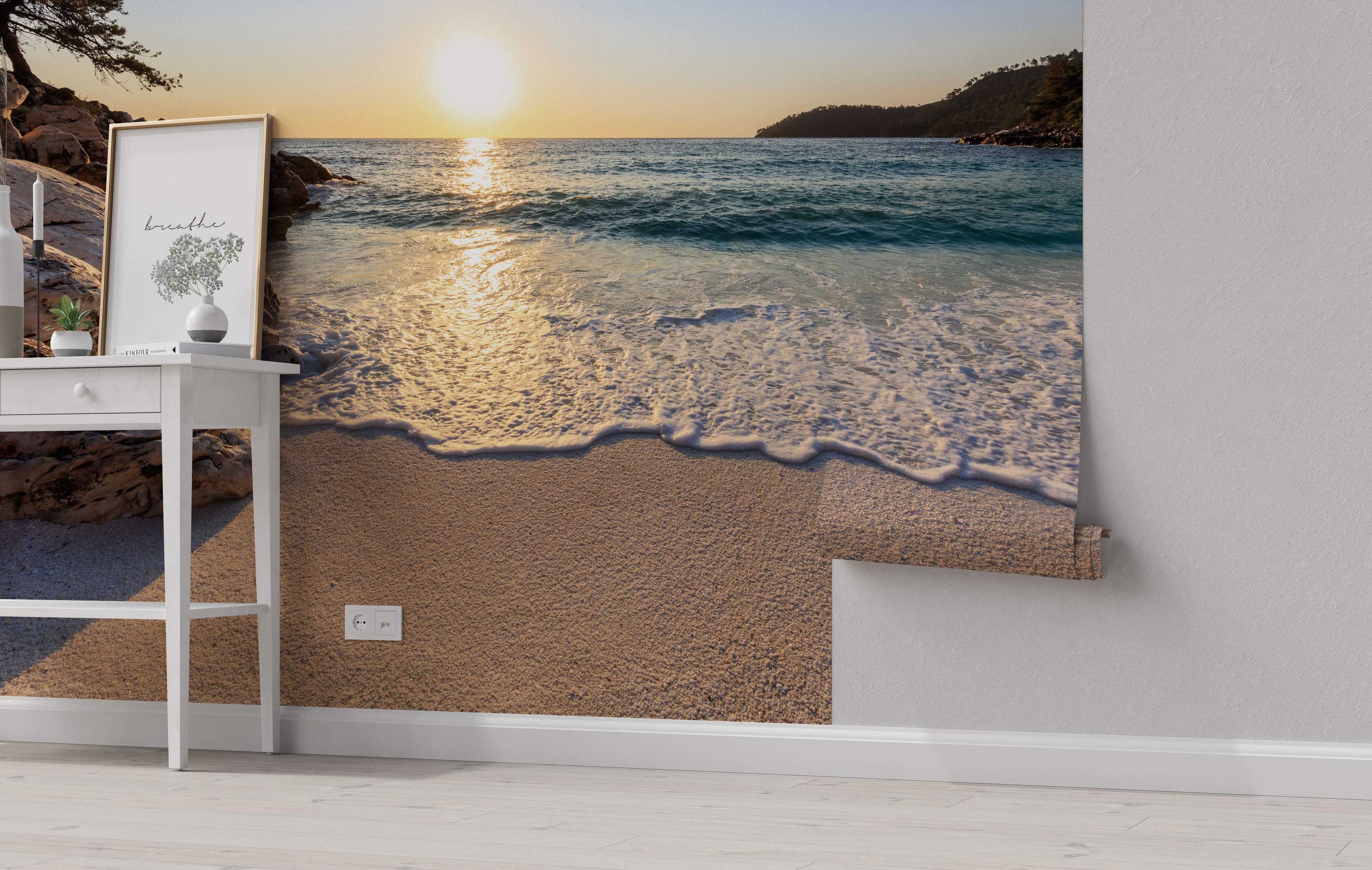 Photographic wall mural showing a golden sunset over a blue ocean with waves washing onto a sandy beach.