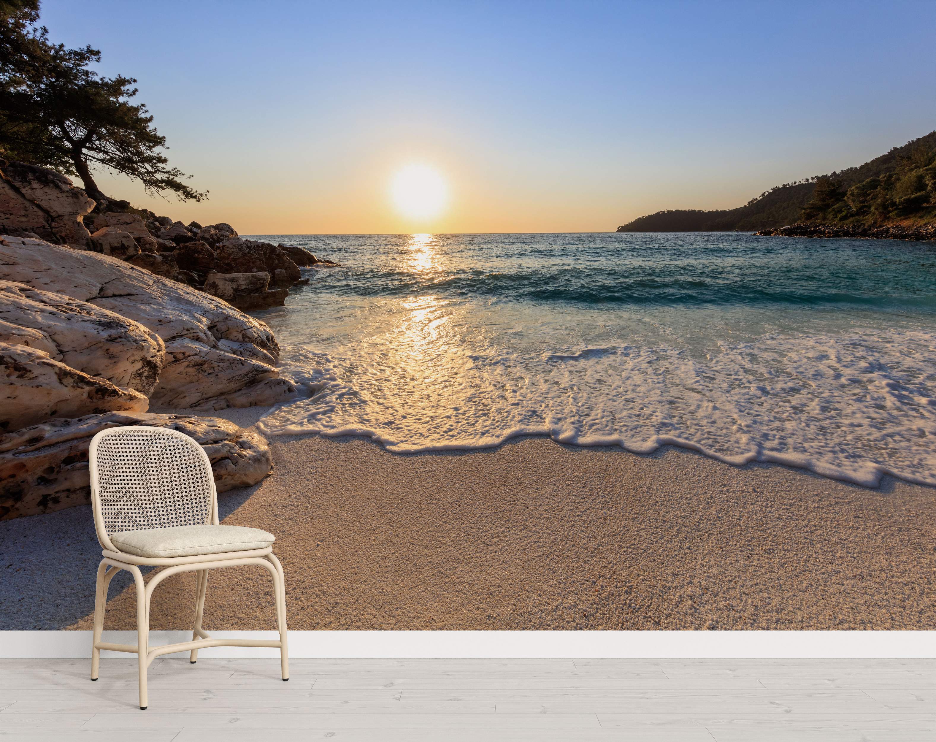 A serene beach mural depicting a golden sunset over calm turquoise waters, with waves gently washing onto sandy shores flanked by rocks and trees.