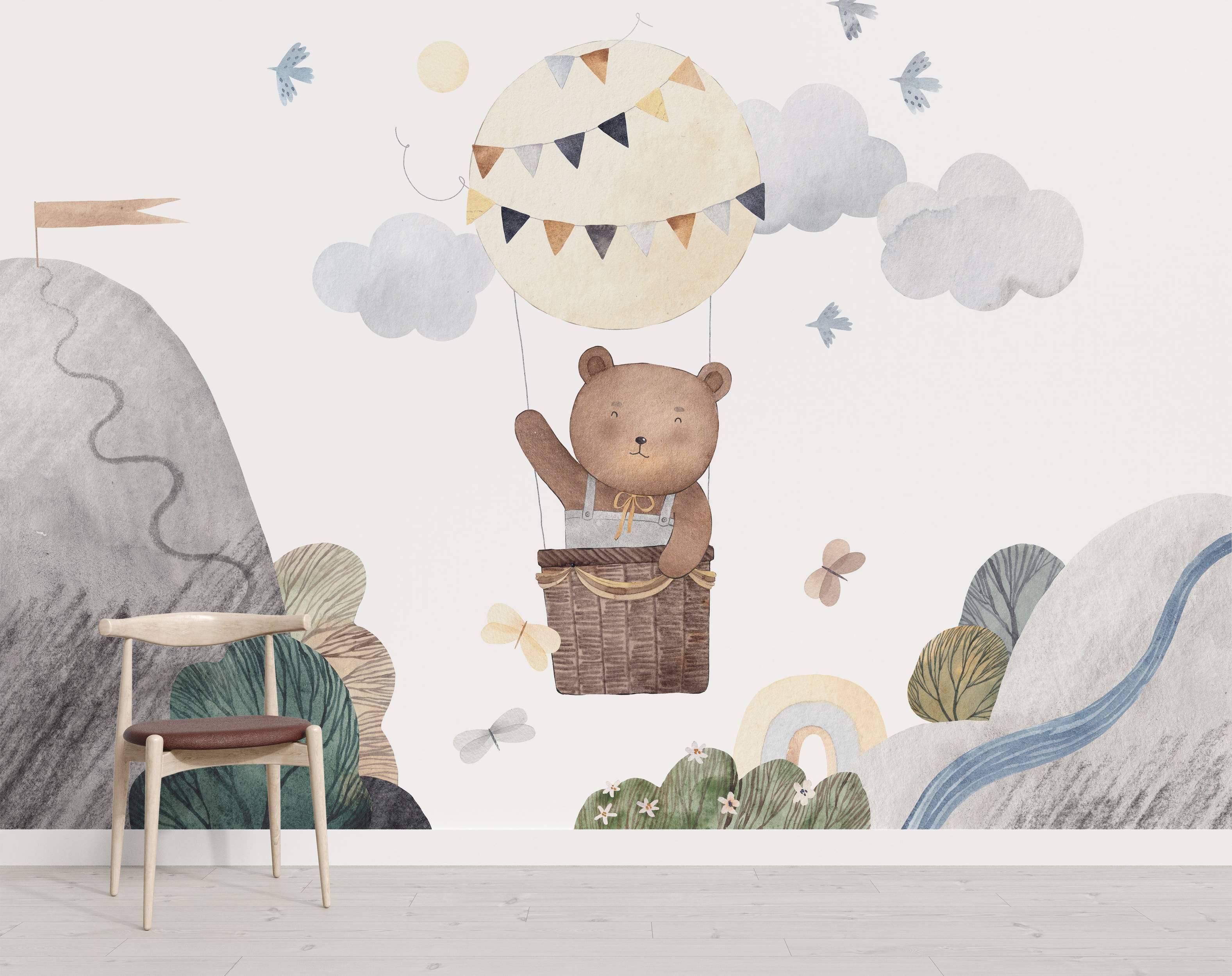 Watercolor mural depicting a bear in a hot air balloon floating over a landscape with mountains, clouds, birds, and a rainbow.