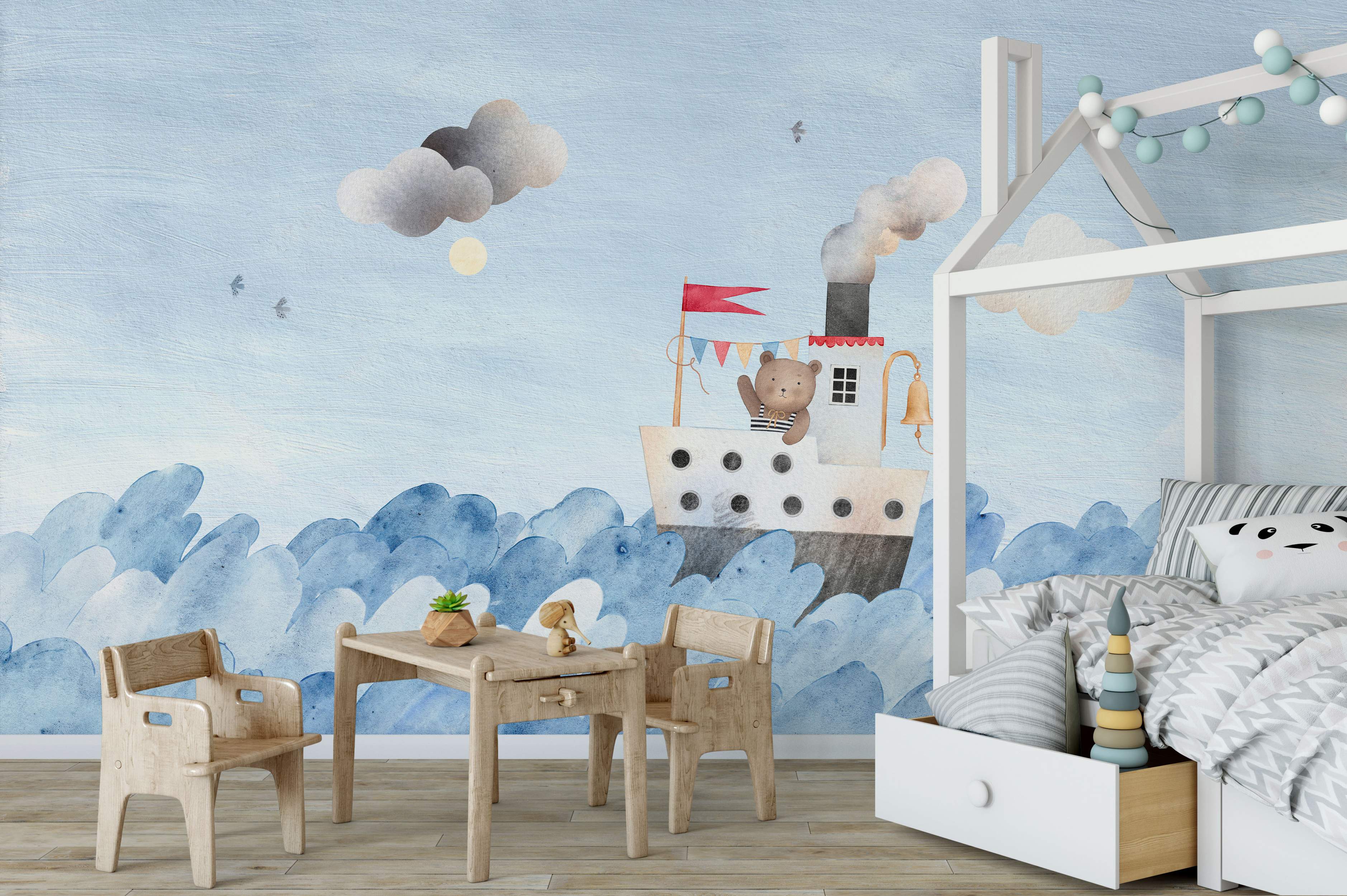 Watercolor mural featuring a teddy bear waving from a steamboat on blue waves under a light blue sky with grey clouds and birds.