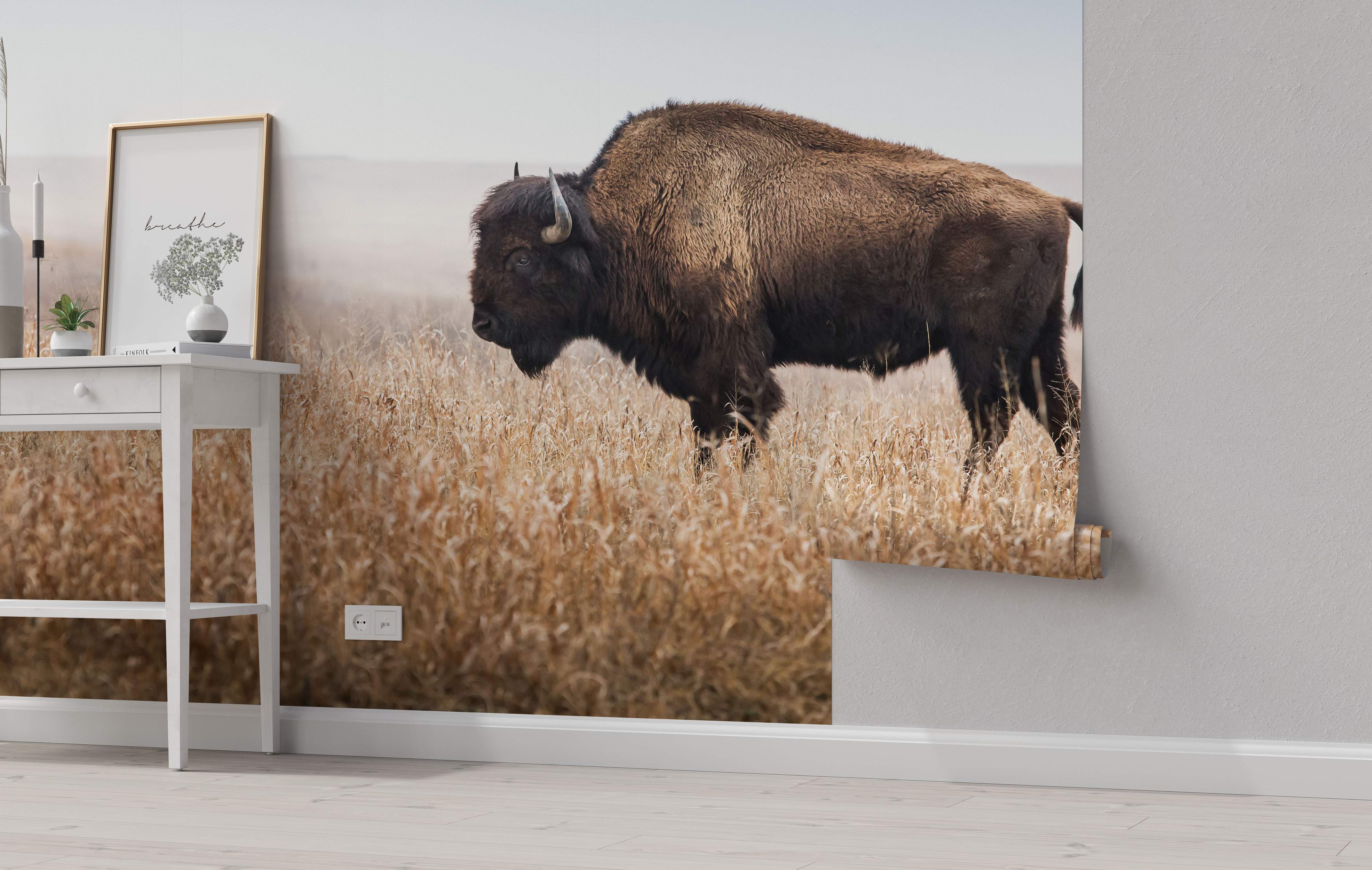 Photorealistic mural depicting a large brown bison standing in a field of tall golden grass beneath a pale, hazy sky.