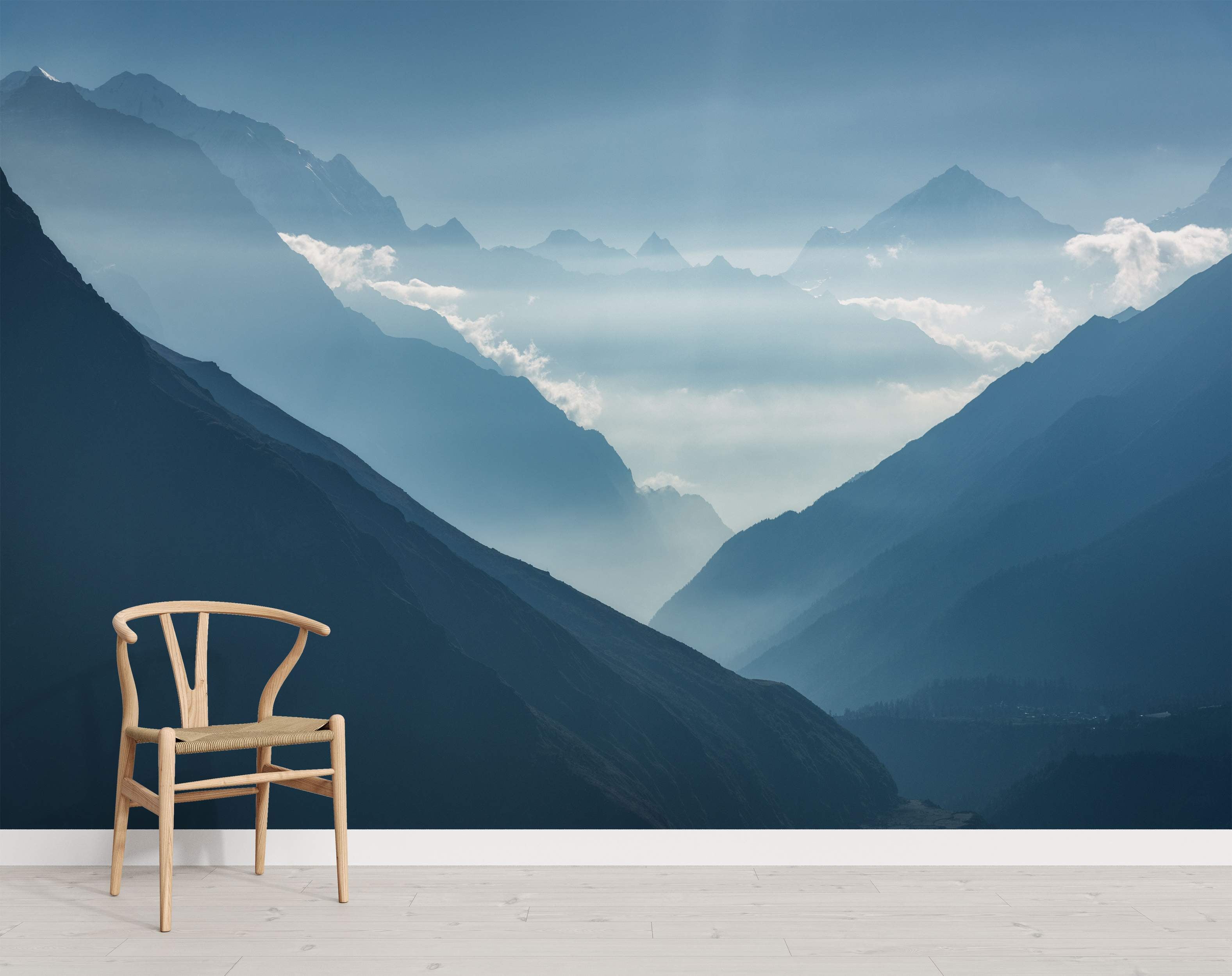 Scenic mural depicting layers of hazy blue mountain ranges receding into a misty valley under a pale blue sky.