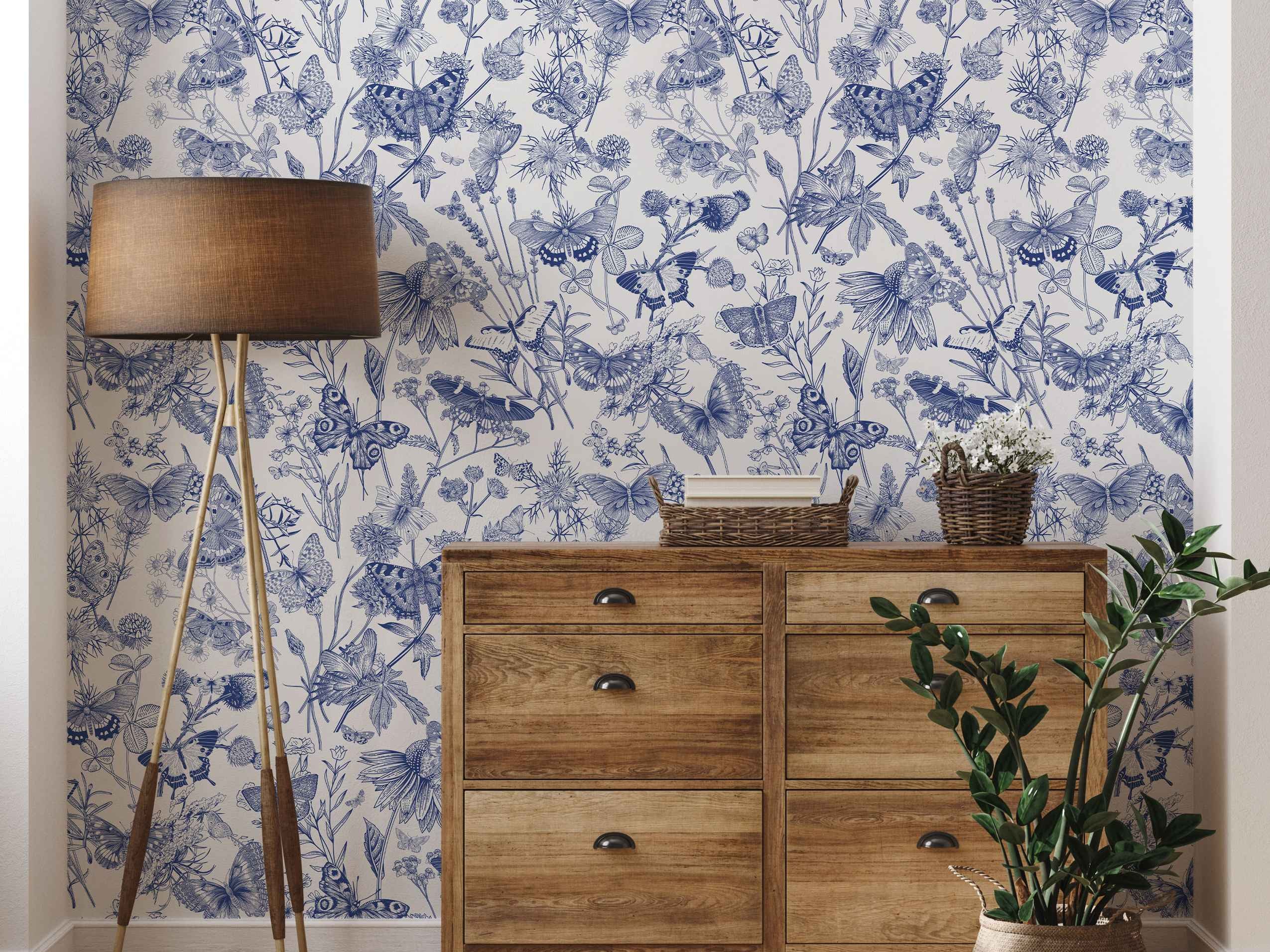 Detailed blue etching-style illustrations of butterflies, wildflowers, and foliage on a white wallpaper background.