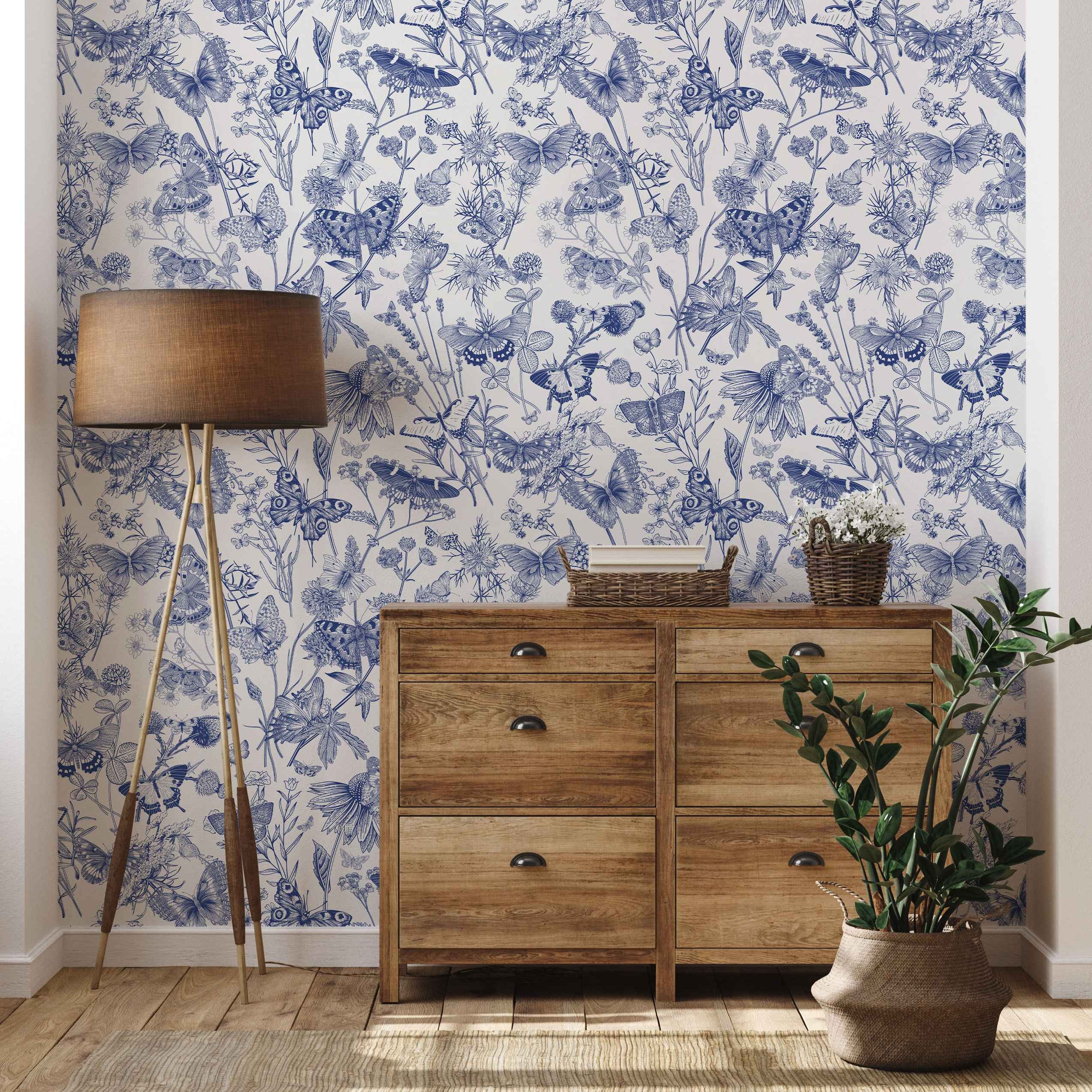Detailed blue etching-style illustrations of butterflies, wildflowers, and foliage on a white wallpaper background.