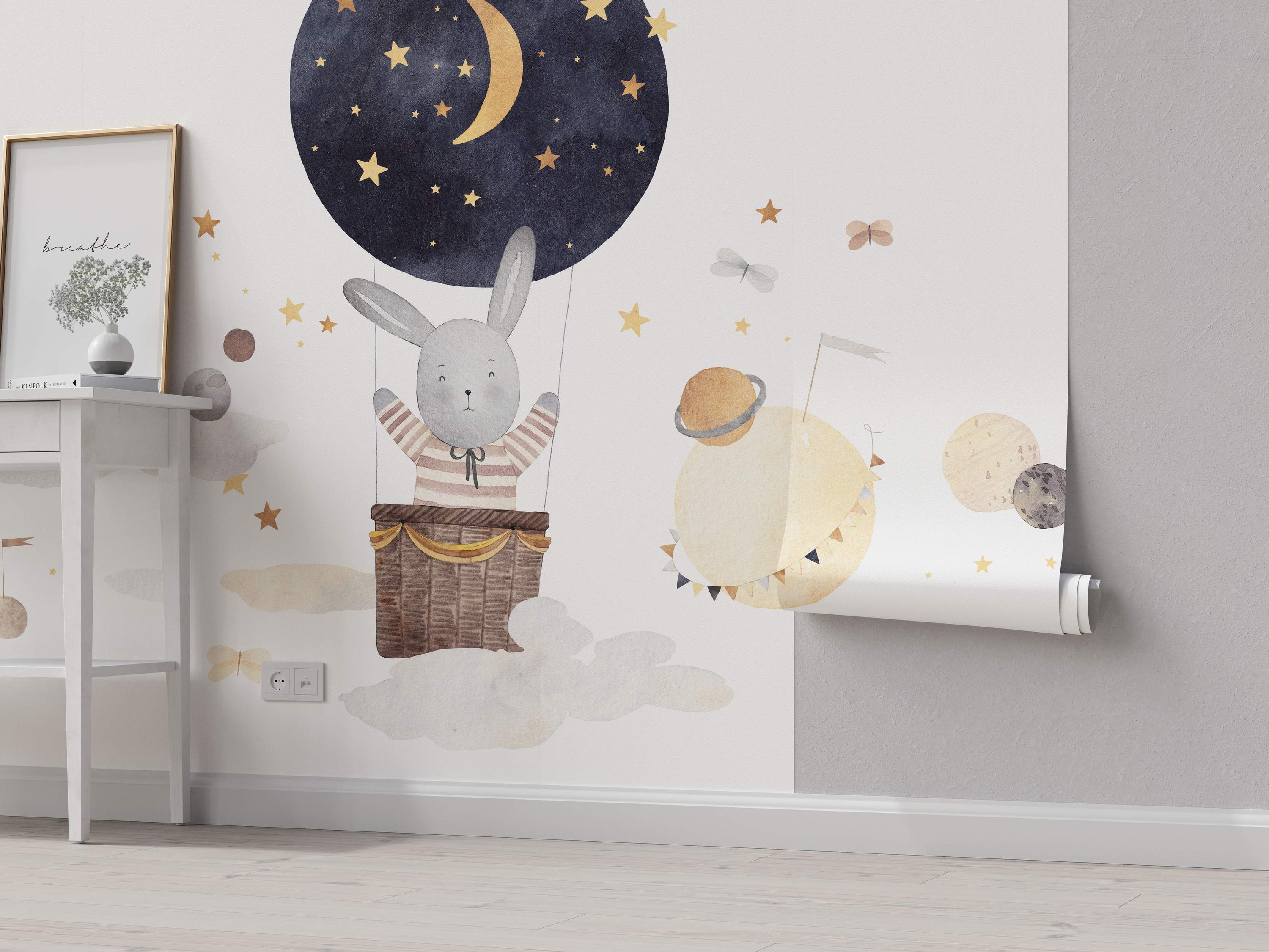 Whimsical mural featuring a gray bunny in a night-sky hot air balloon with gold stars, surrounded by watercolor planets and clouds.