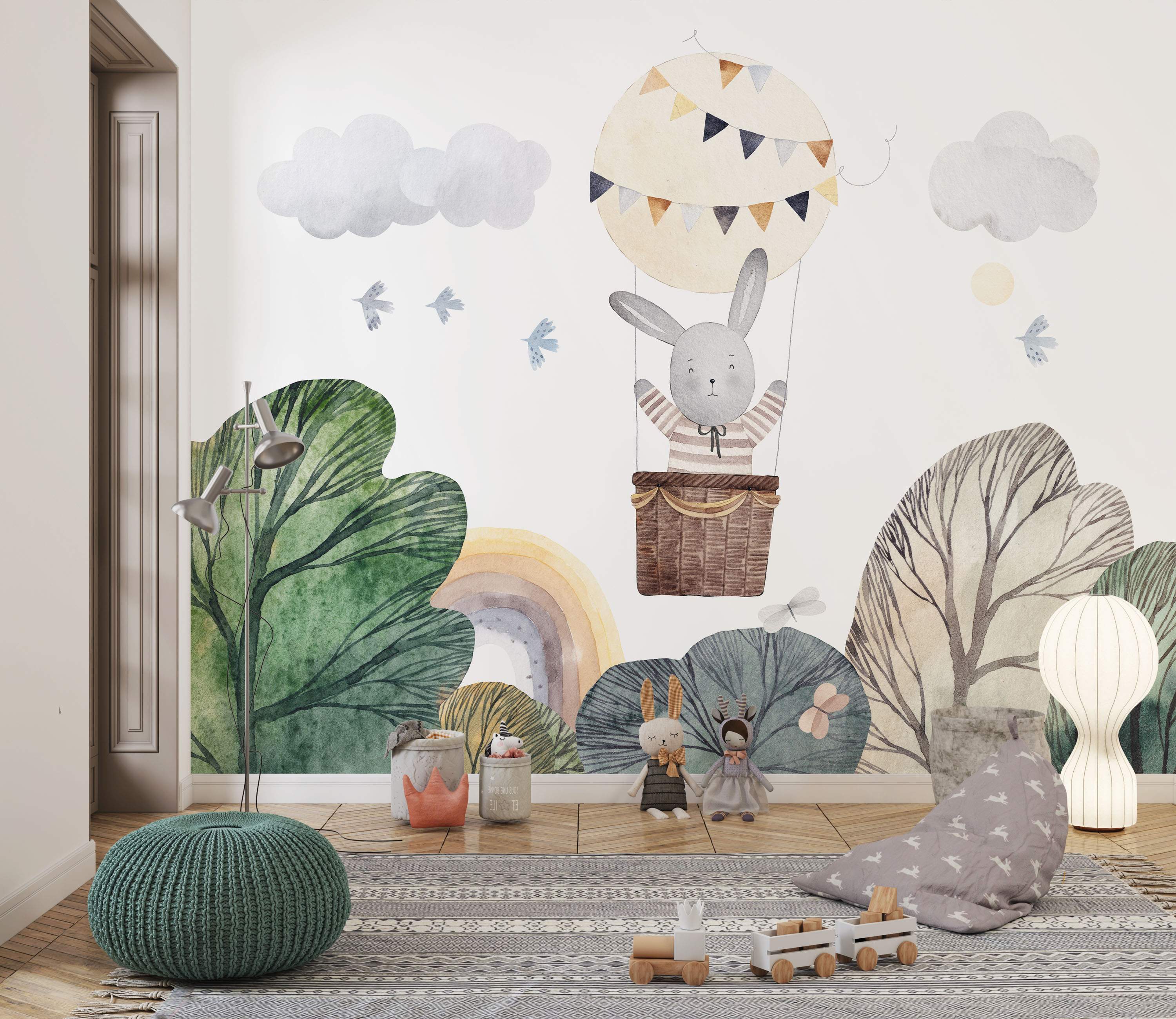 Watercolor mural depicting a gray bunny in a hot air balloon floating over stylized green and brown trees, with clouds and birds.