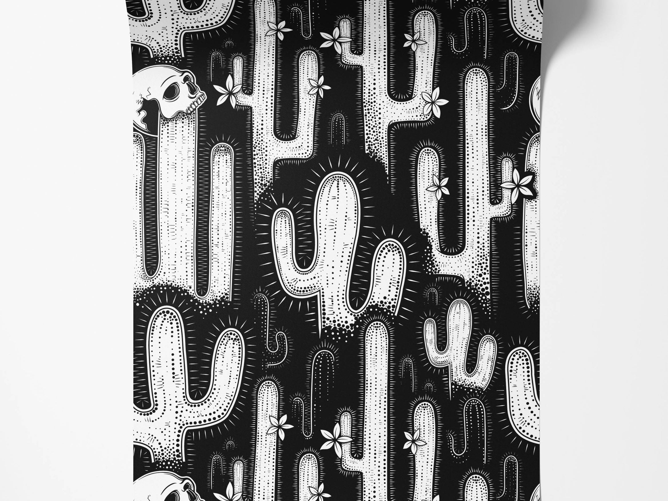 A bold, black and white wallpaper with a graphic pattern of cacti, skulls, and flowers in a linocut style.