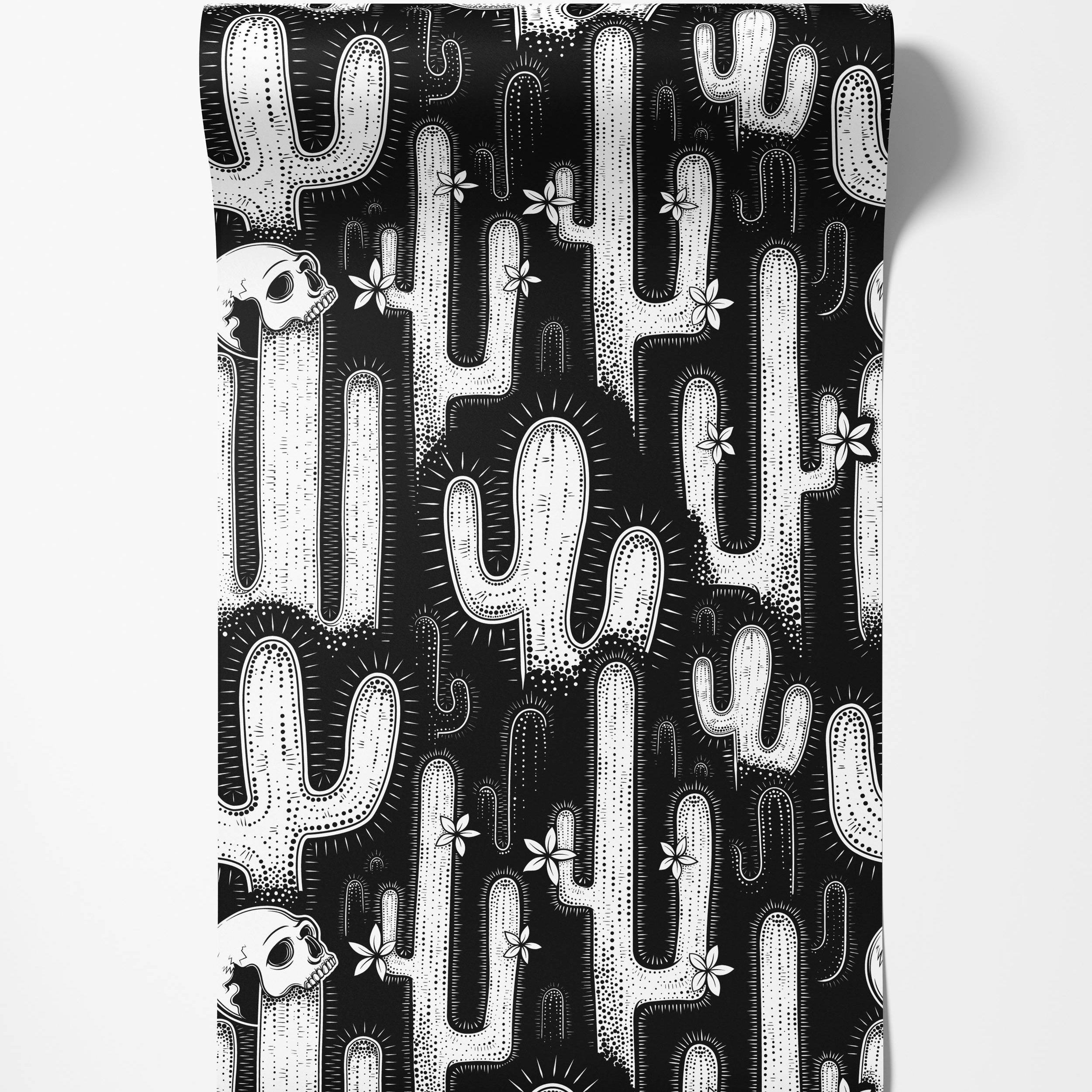 A bold, black and white wallpaper with a graphic pattern of cacti, skulls, and flowers in a linocut style.