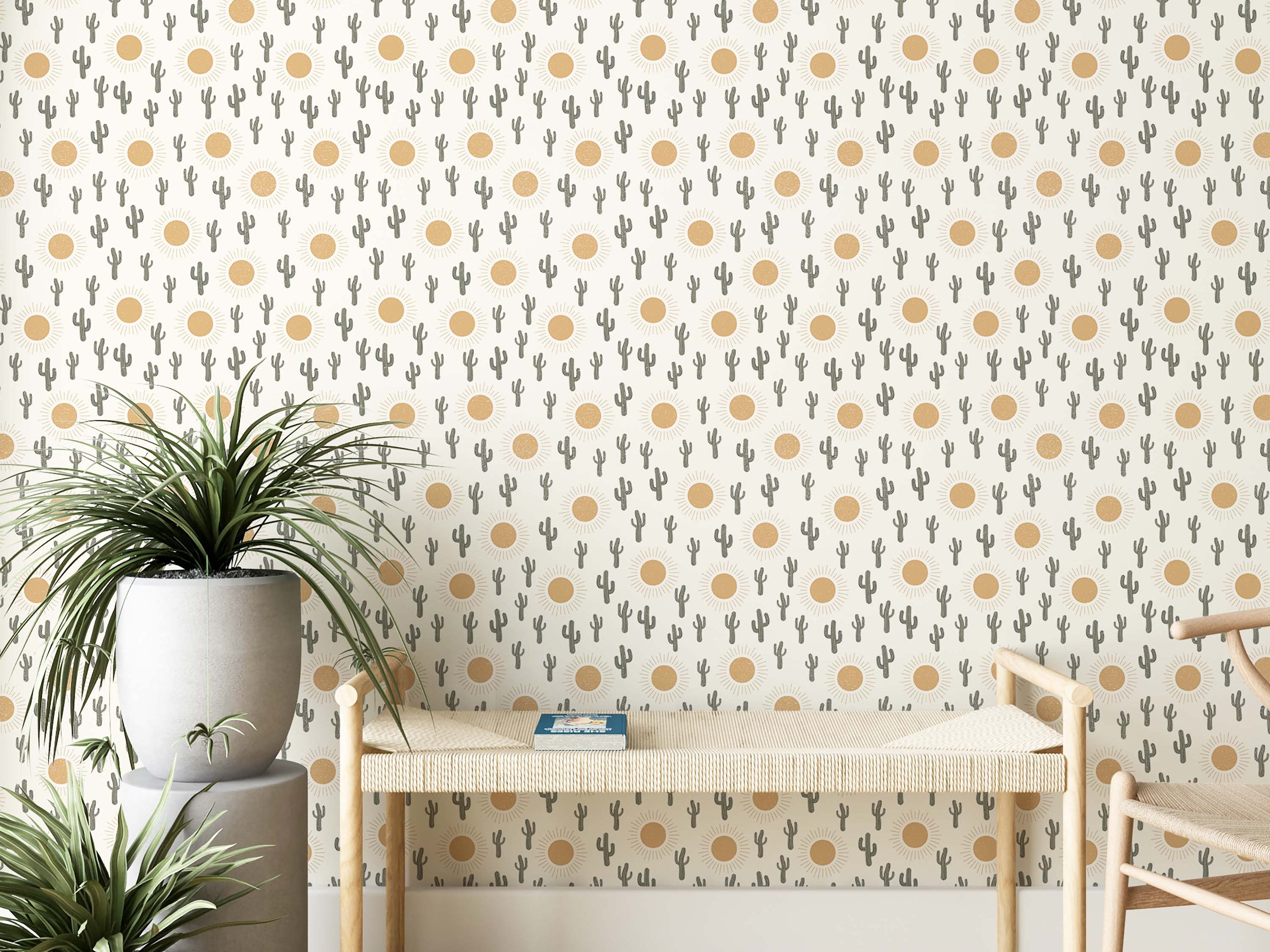 A whimsical wallpaper with a repeating pattern of gray-green cacti and golden-yellow suns on an off-white background.