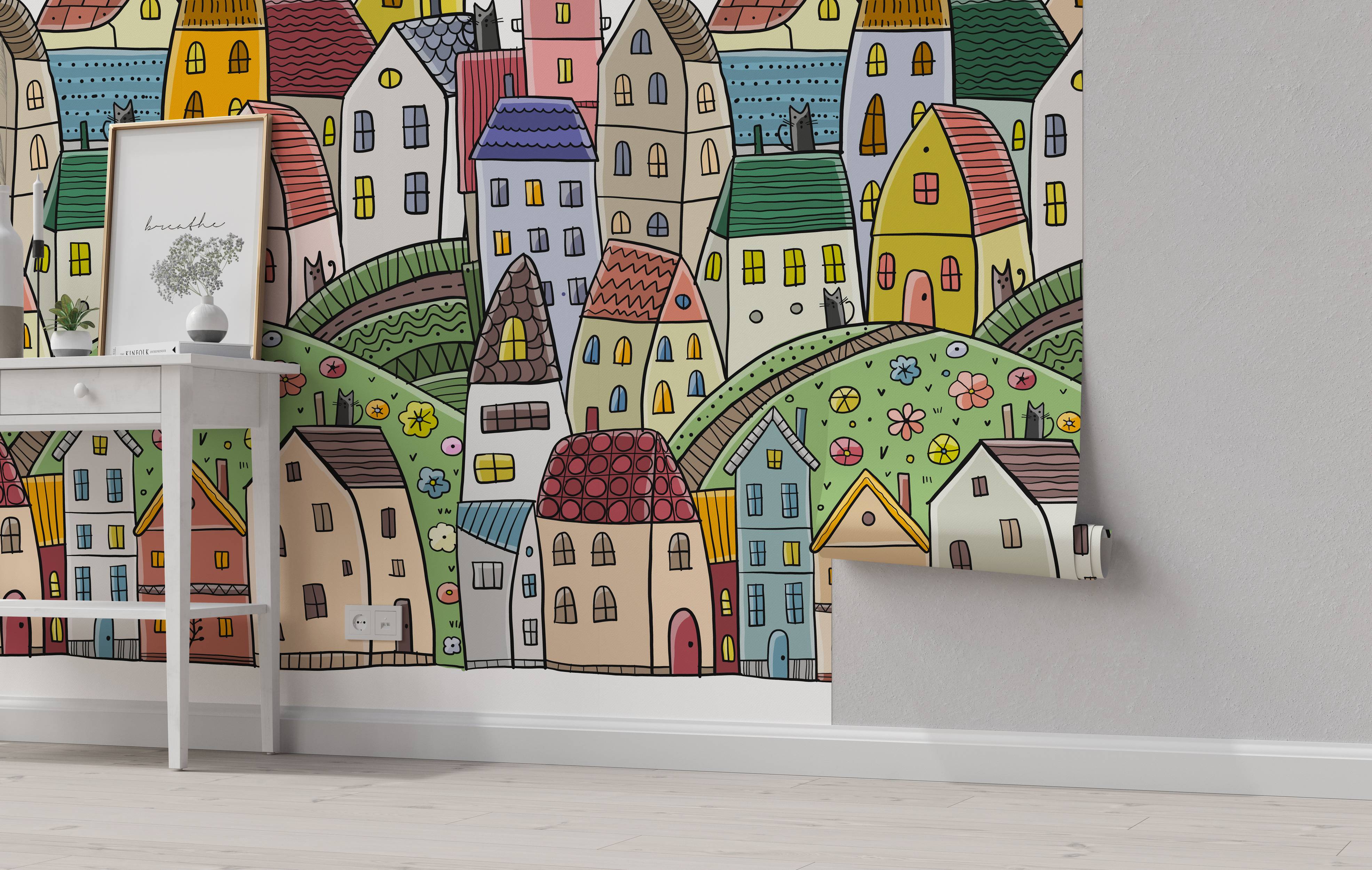 Whimsical cartoon mural depicting a colorful town with various houses nestled on rolling green hills, drawn with black outlines.