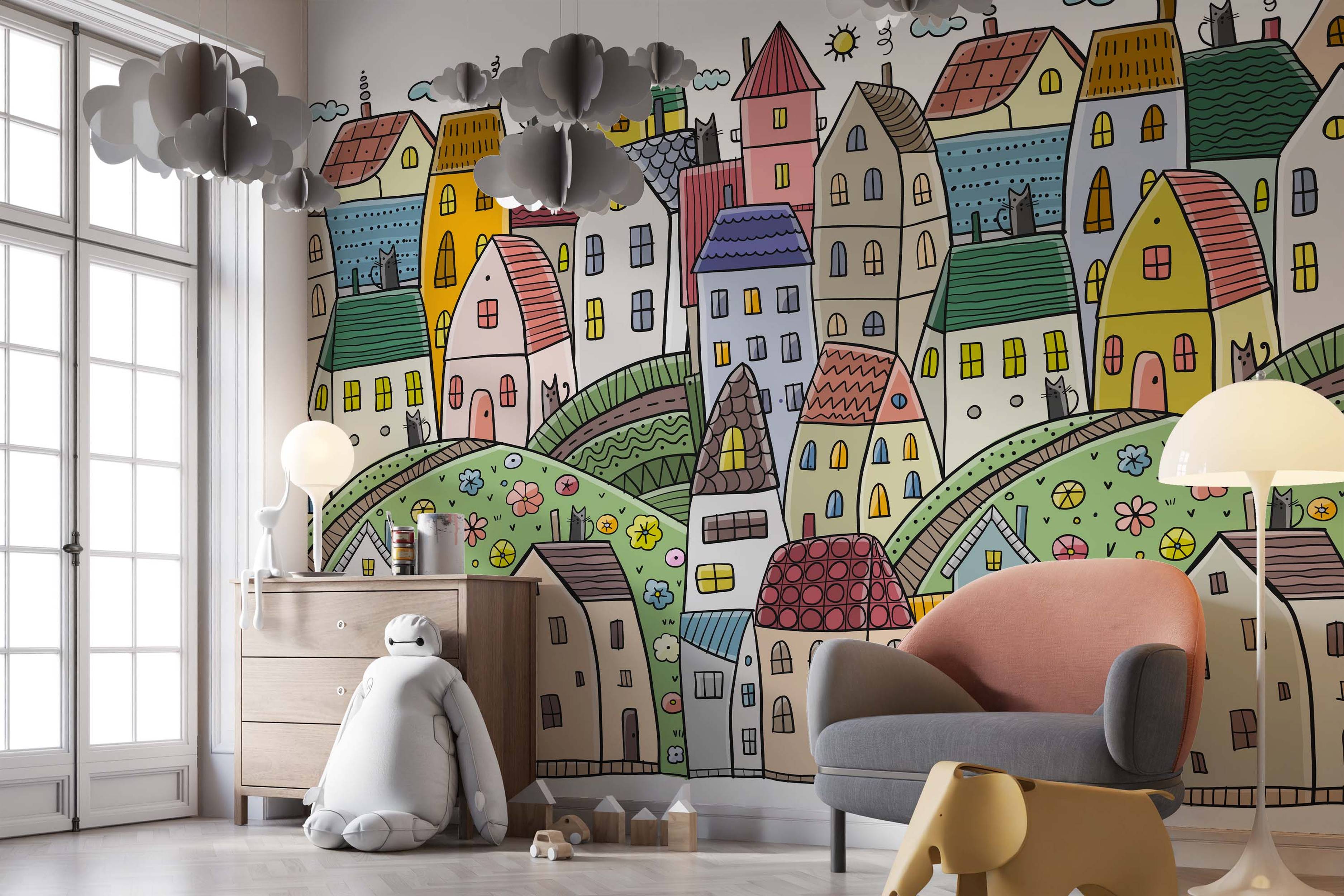 Whimsical cartoon village mural featuring colorful houses on green hills with flowers and cats, drawn in a naive style with black outlines.