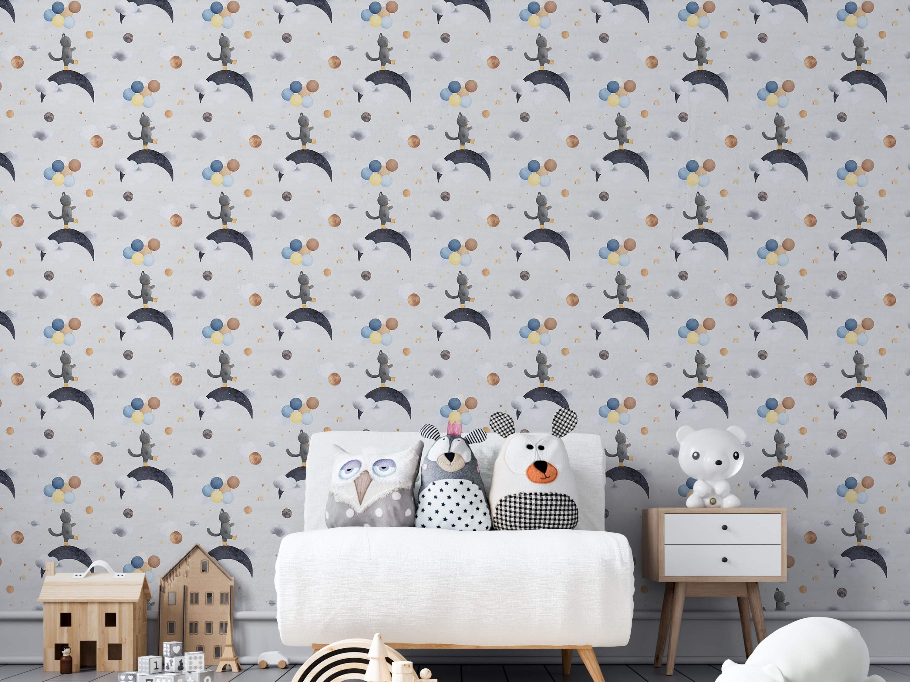 Repeating wallpaper with watercolor gray cats on moons, surrounded by planets, balloons, and clouds in blue, yellow, and gold.