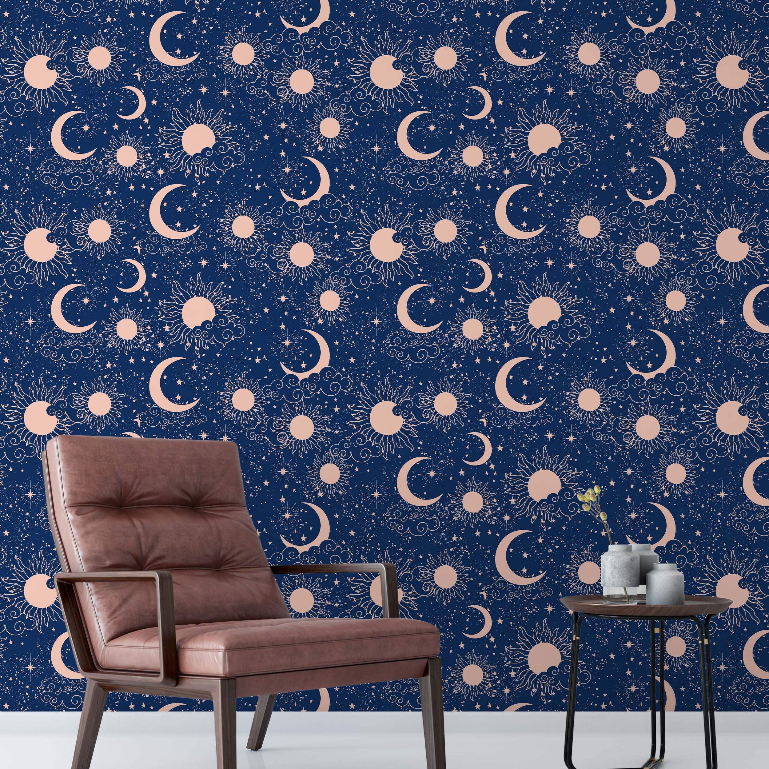 Celestial wallpaper with rose gold suns, crescent moons, stars, and clouds scattered across a deep navy blue background.