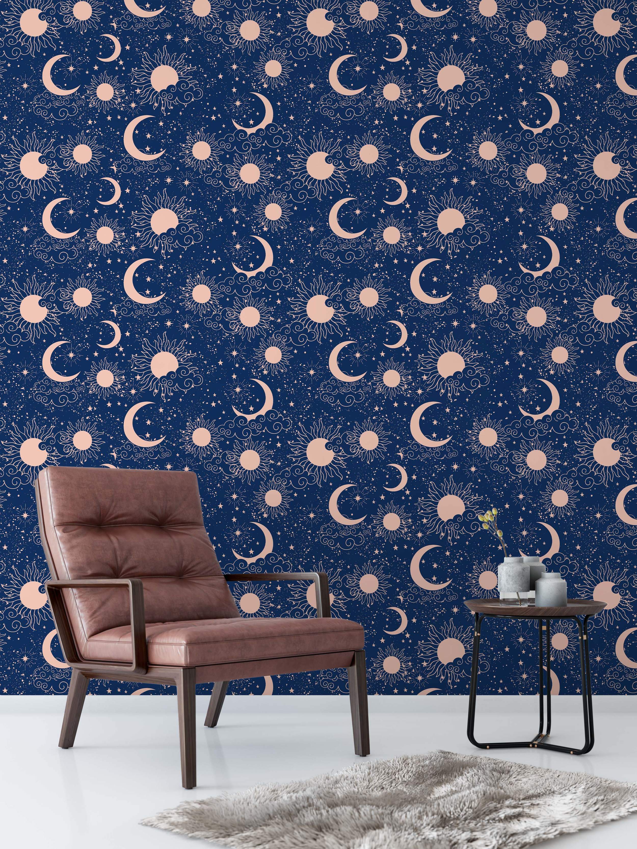 Celestial wallpaper with rose gold suns, crescent moons, stars, and clouds scattered across a deep navy blue background.