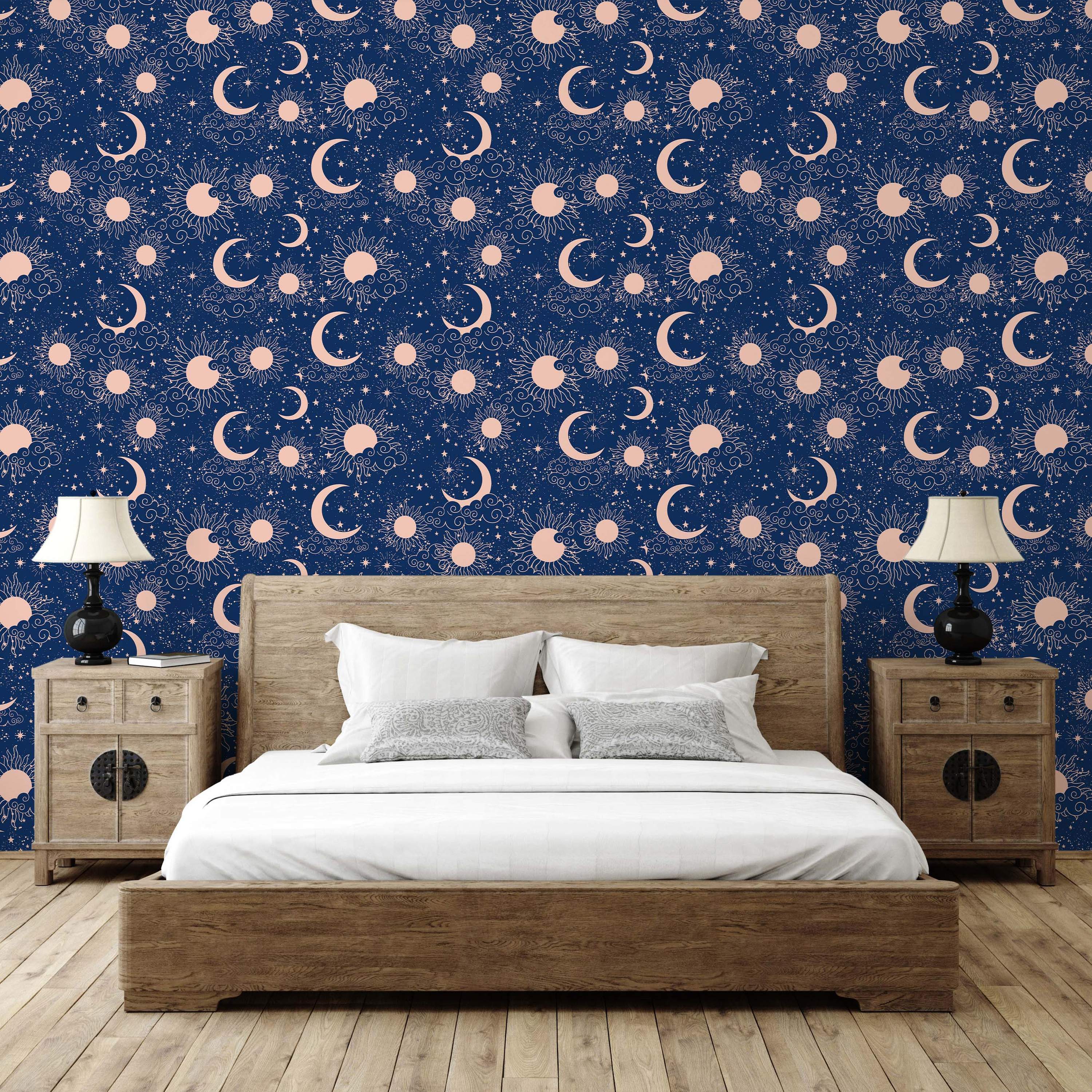 Celestial wallpaper with blush pink suns, crescent moons, stars, and clouds scattered on a dark navy blue background.