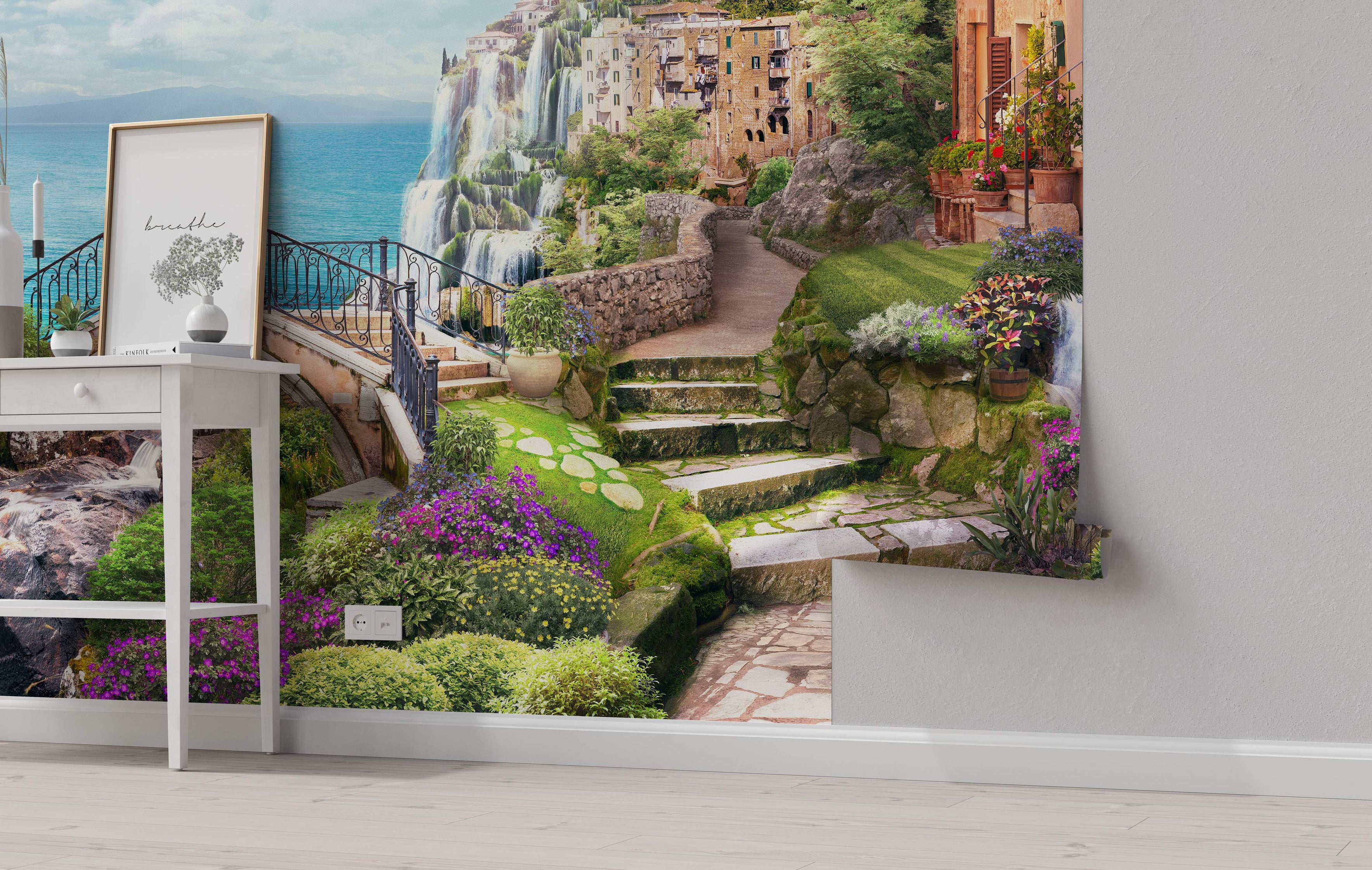 Mural depicting a scenic village built into a cliff by the sea, featuring large waterfalls, stone steps, and lush green foliage.