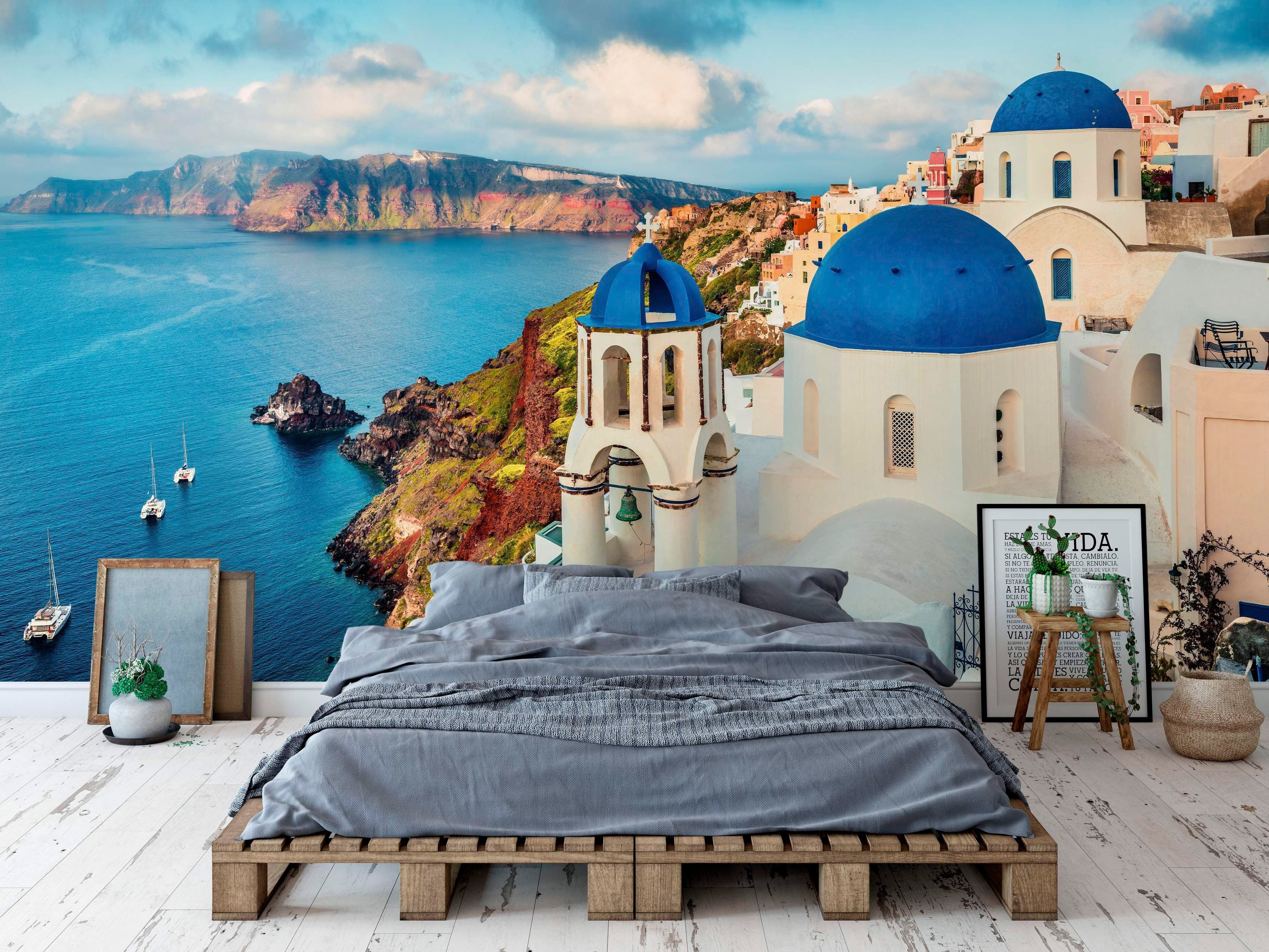 Scenic mural depicting white Greek cliffside buildings with vibrant blue domes overlooking a deep blue sea under a cloudy sky.