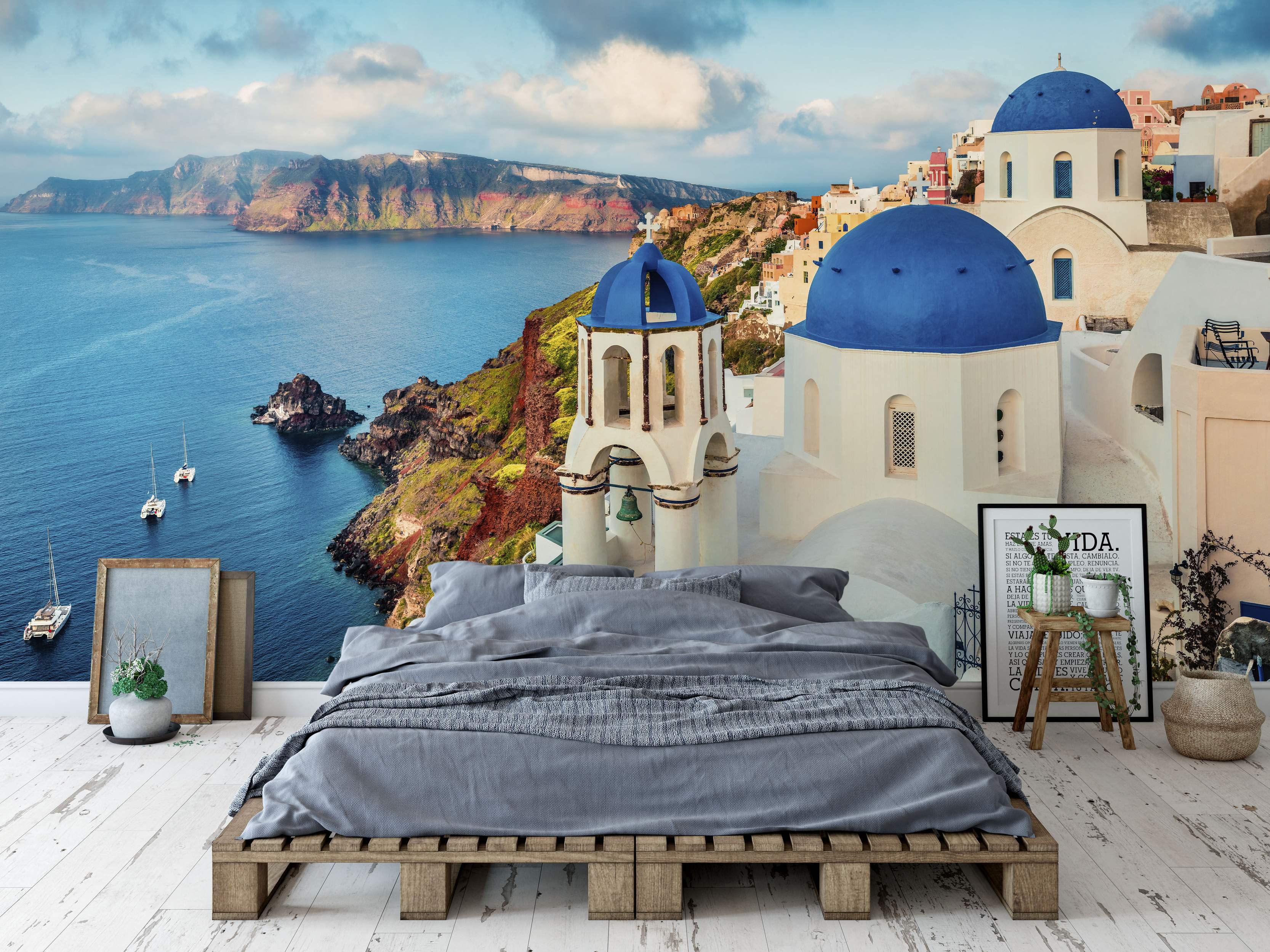 Scenic mural depicting white Greek cliffside buildings with vibrant blue domes overlooking a deep blue sea under a cloudy sky.