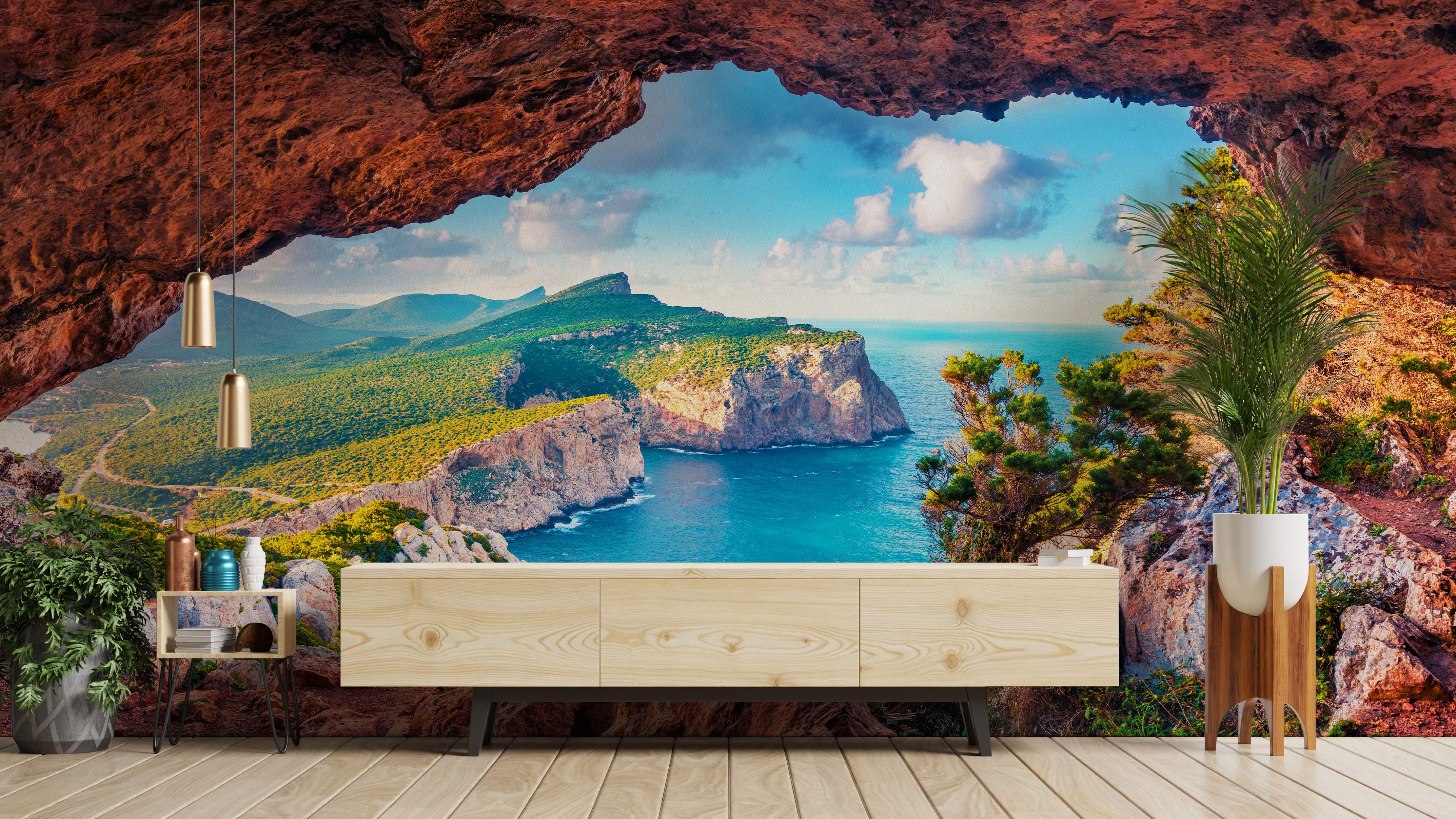 Photorealistic mural featuring a view from a red rock cave opening onto green coastal cliffs, blue ocean waters, and sky.