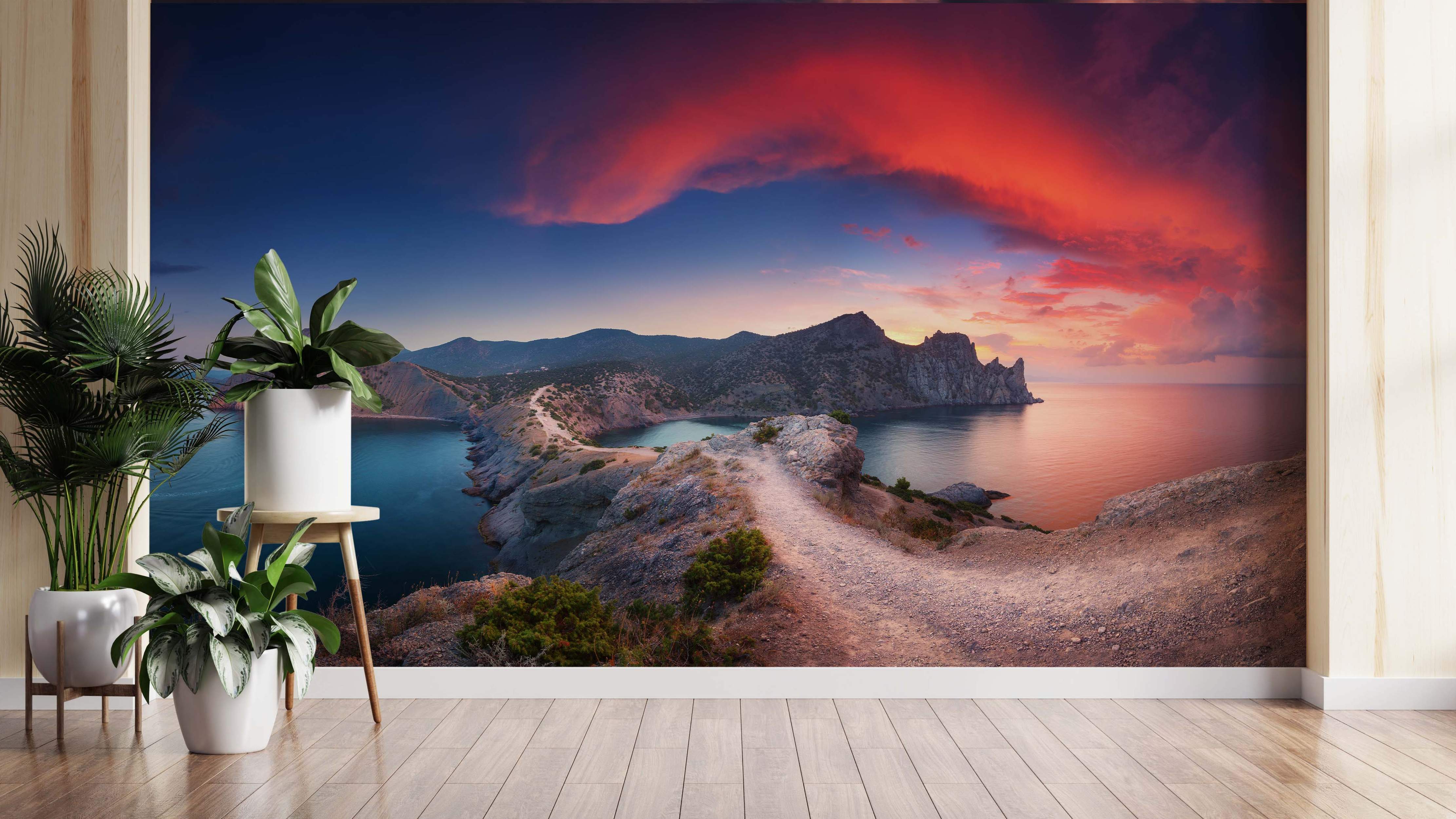 Scenic coastal landscape mural with rocky cliffs, a path, and blue water under a dramatic red and blue sunset sky.