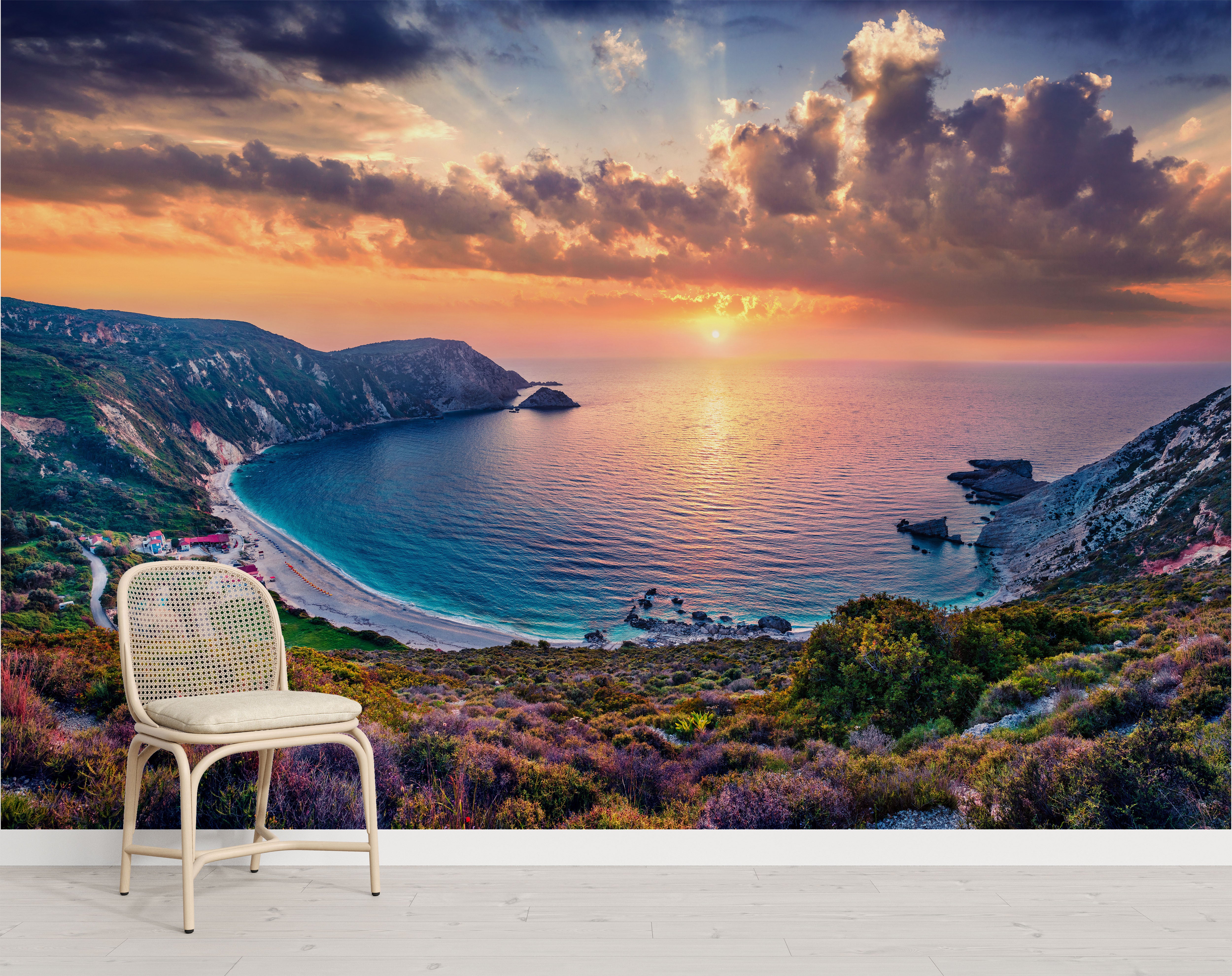 Mural depicting a dramatic coastal sunset over a blue bay, with orange clouds, steep cliffs, a beach, and colorful hills.