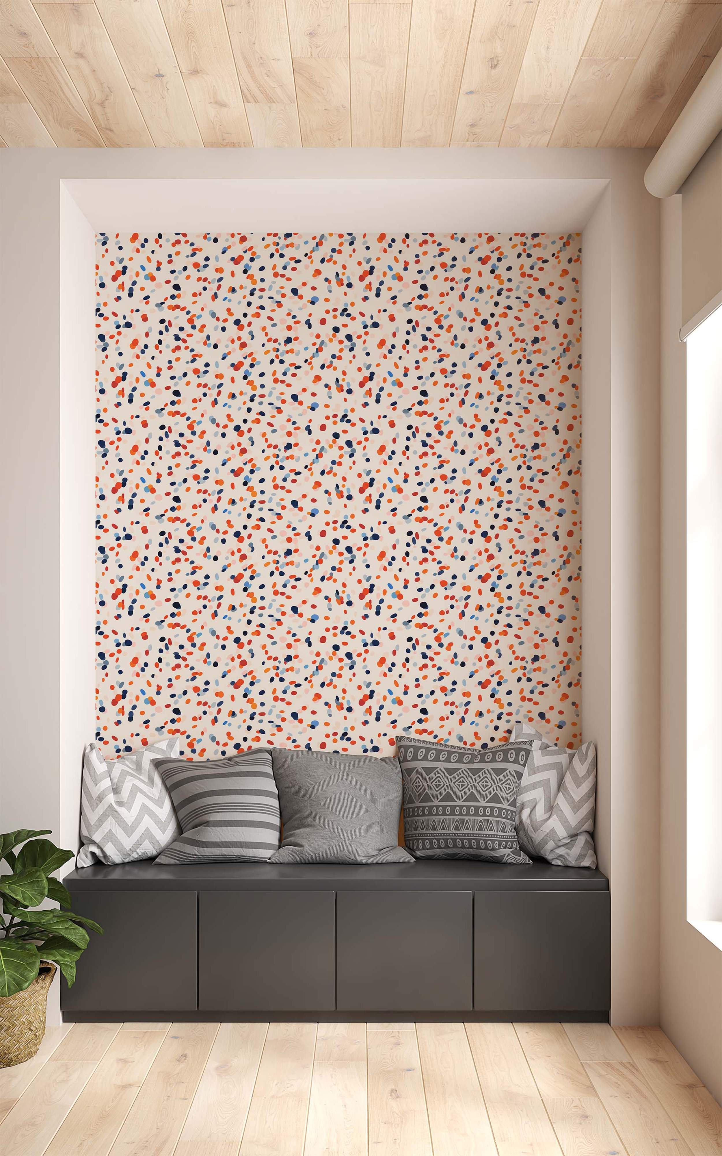 Wallpaper featuring a random confetti pattern of orange, dark blue, light blue, and red spots on a cream background.