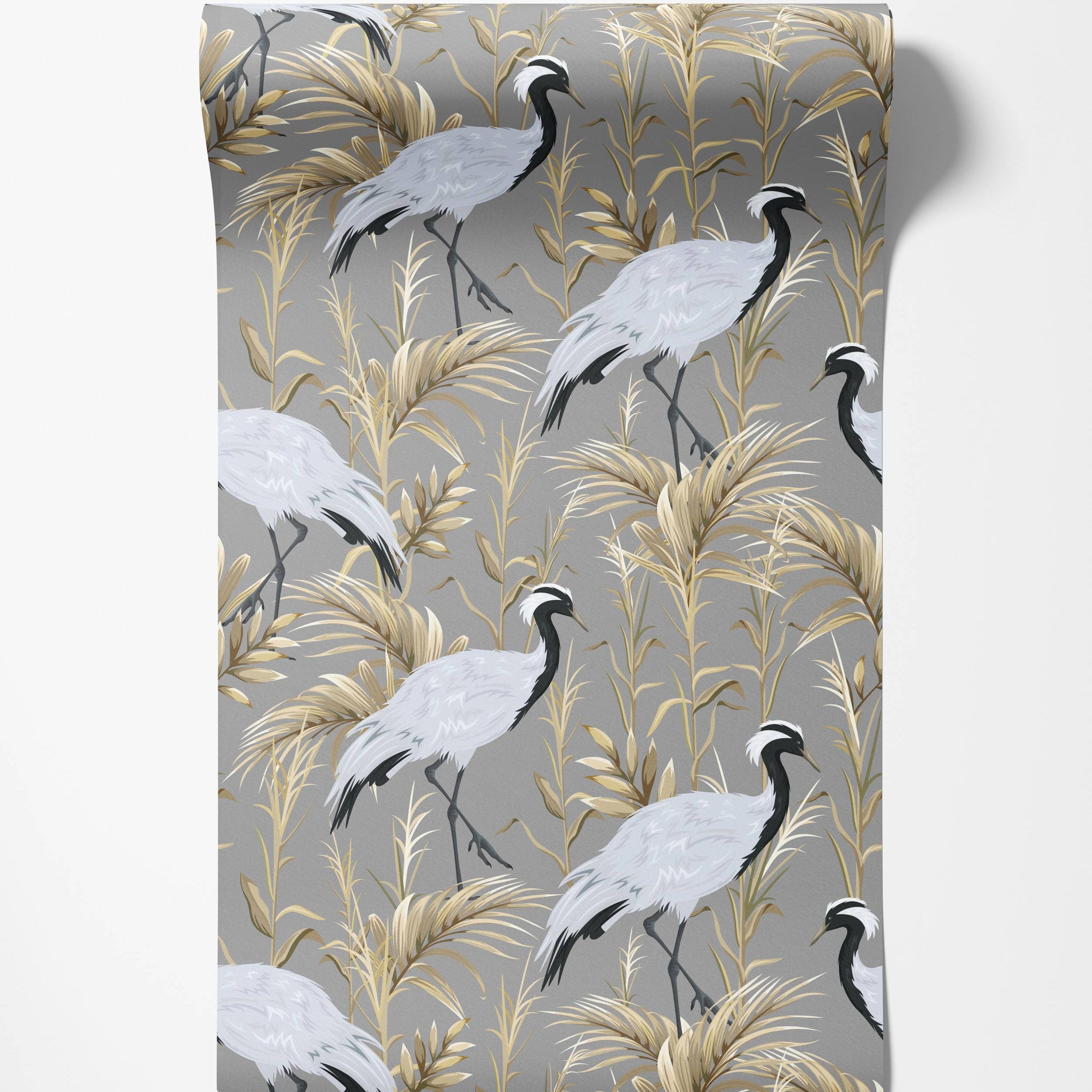 Elegant wallpaper with a repeating pattern of grey cranes with black and white heads among golden foliage on a grey background.