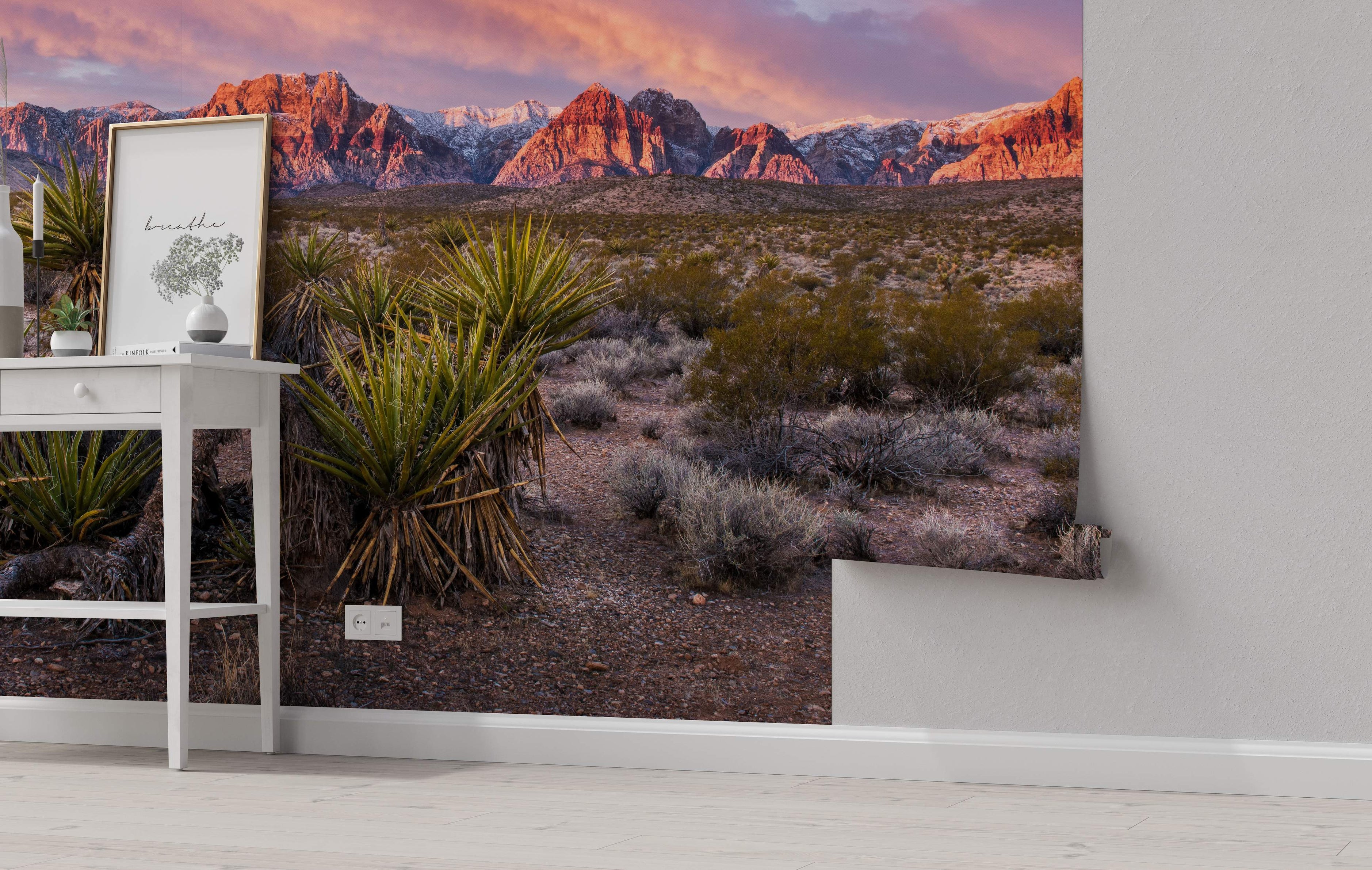 Photorealistic mural depicting a desert landscape with red mountains under a pink sunset sky, featuring yucca plants in the foreground.
