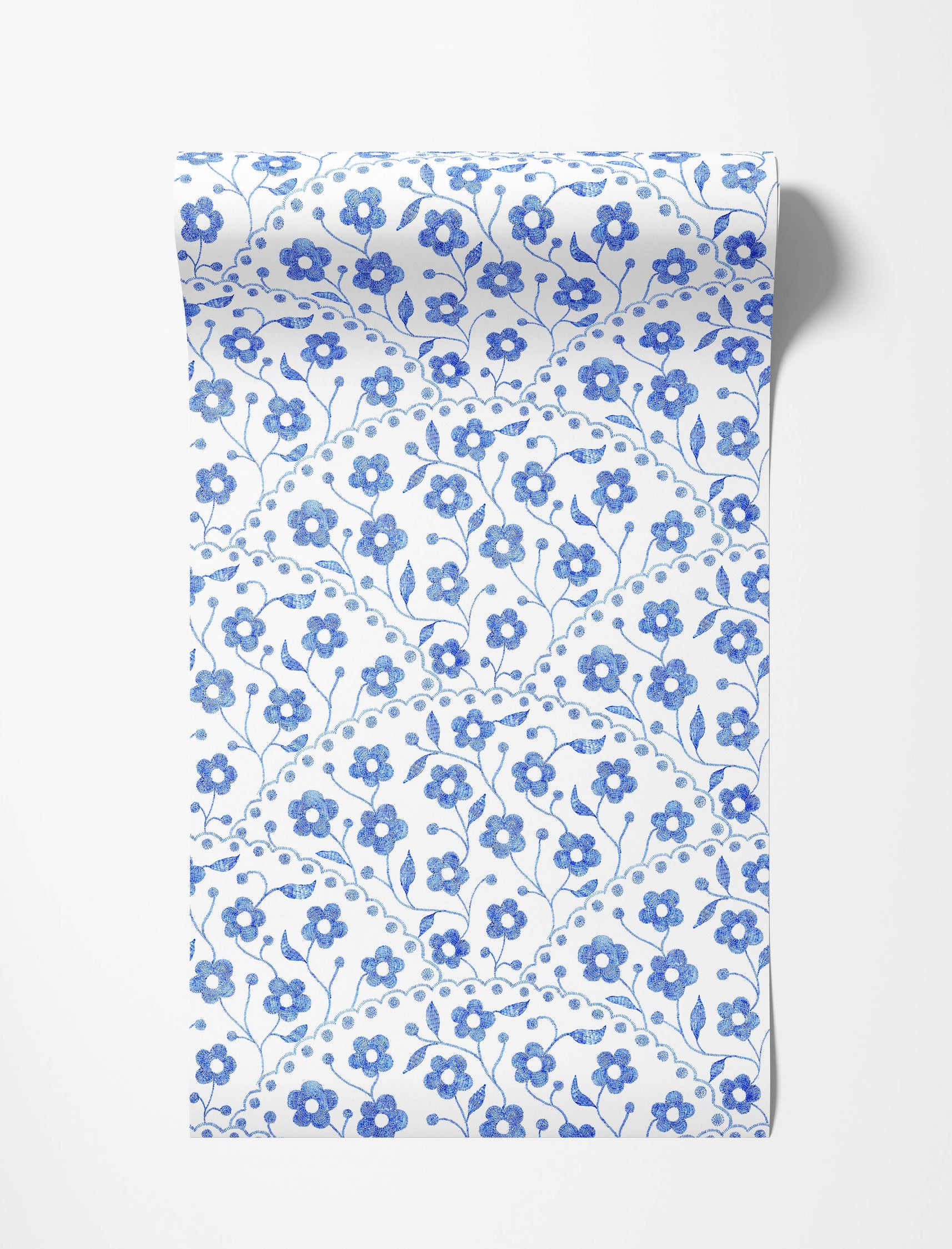 Charming wallpaper with a repeating pattern of blue embroidered-style flowers and curving stems on a white background.