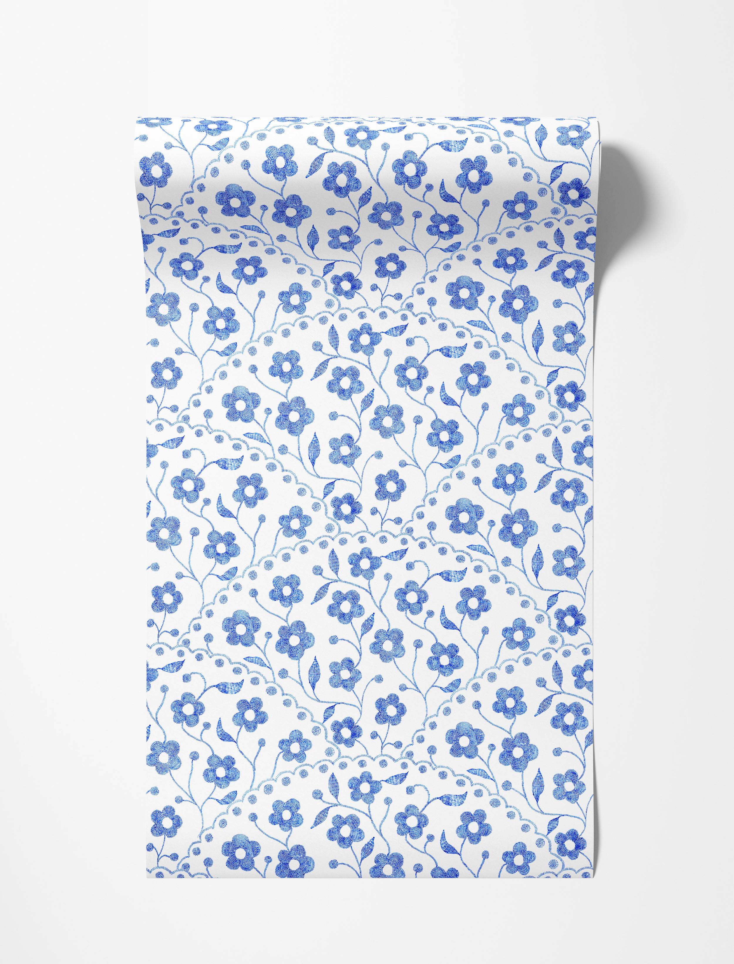 Charming wallpaper with a repeating pattern of blue embroidered-style flowers and curving stems on a white background.