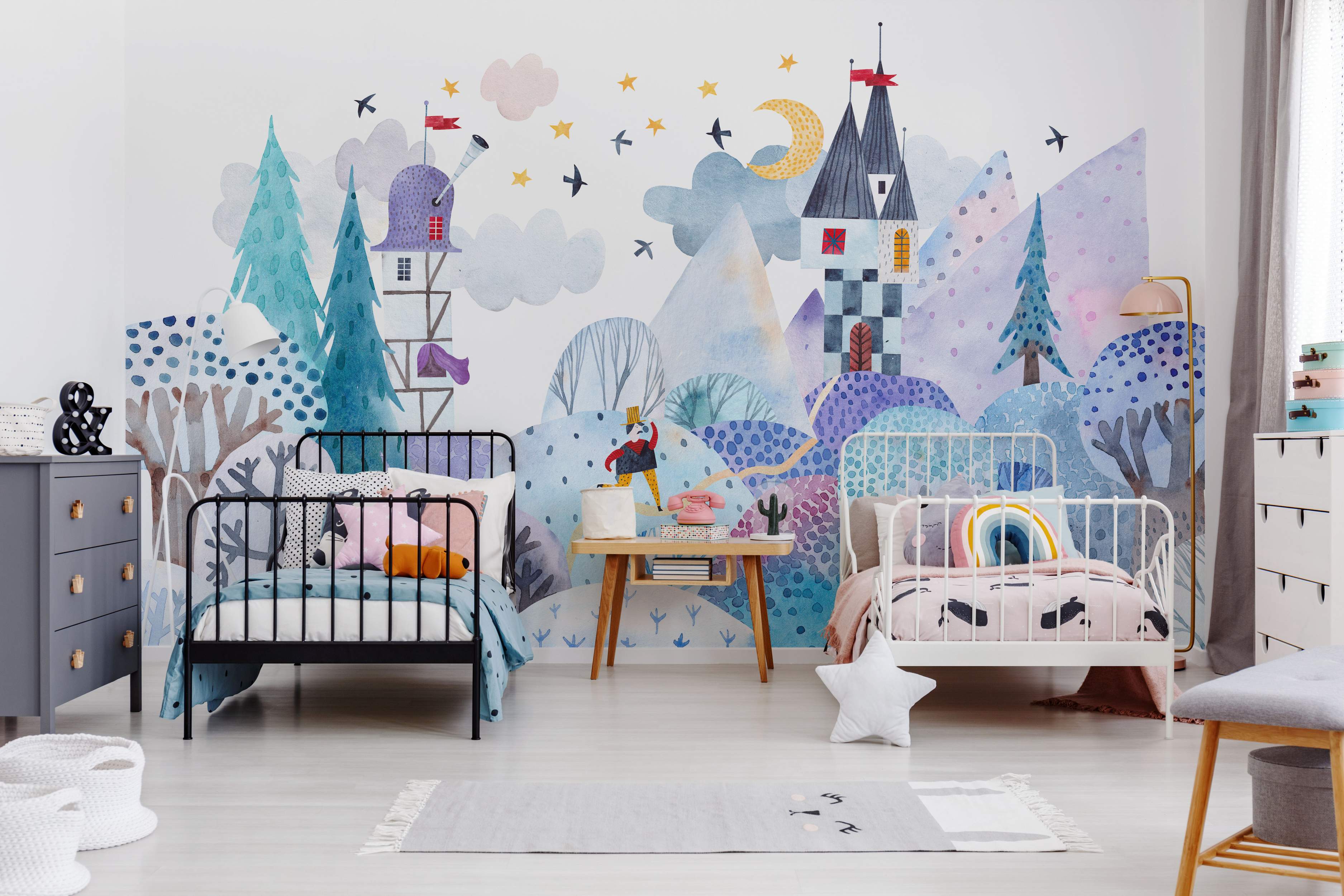 Watercolor mural depicting a whimsical landscape with blue and purple hills, stylized trees, castles, clouds, yellow moon, and stars.