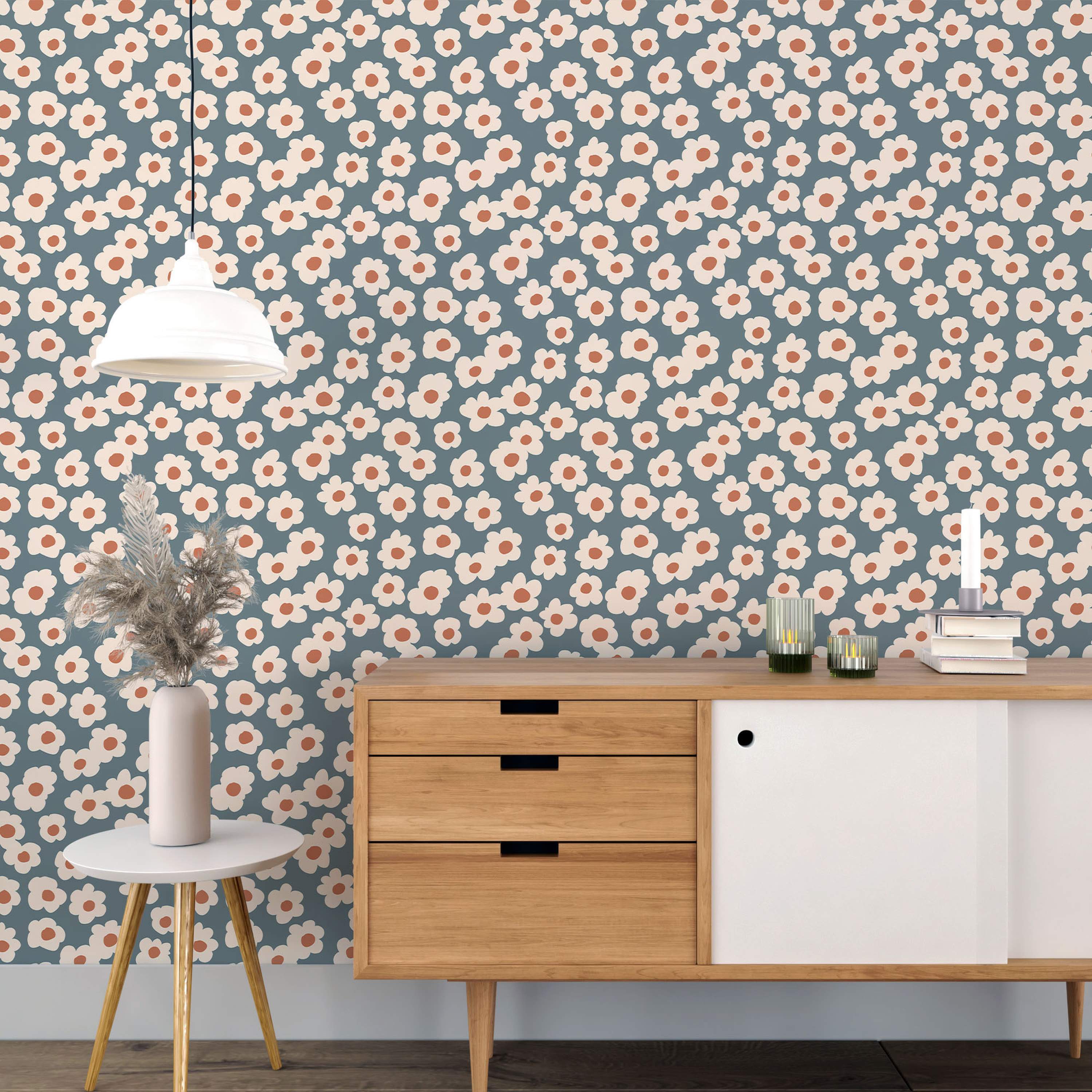 Retro wallpaper featuring simple beige flowers with rust orange centers scattered across a muted blue-gray background.