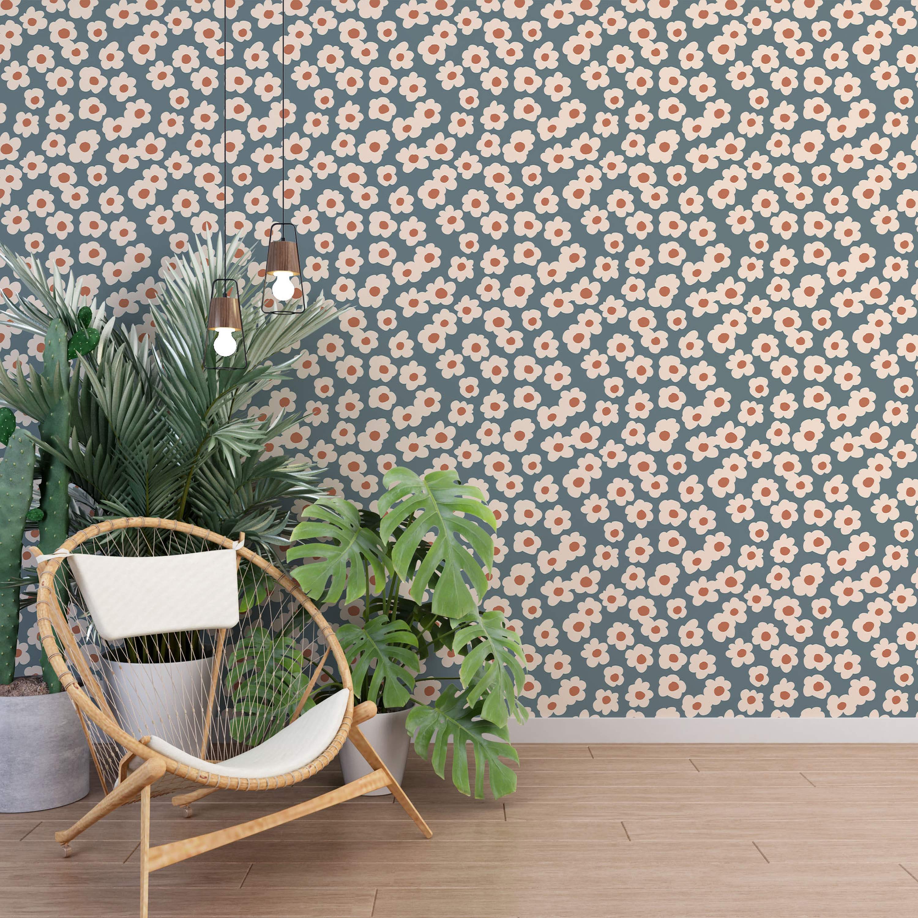 Wallpaper featuring a scattered pattern of simple, cream-colored daisy flowers with terracotta centers on a muted blue-gray background.