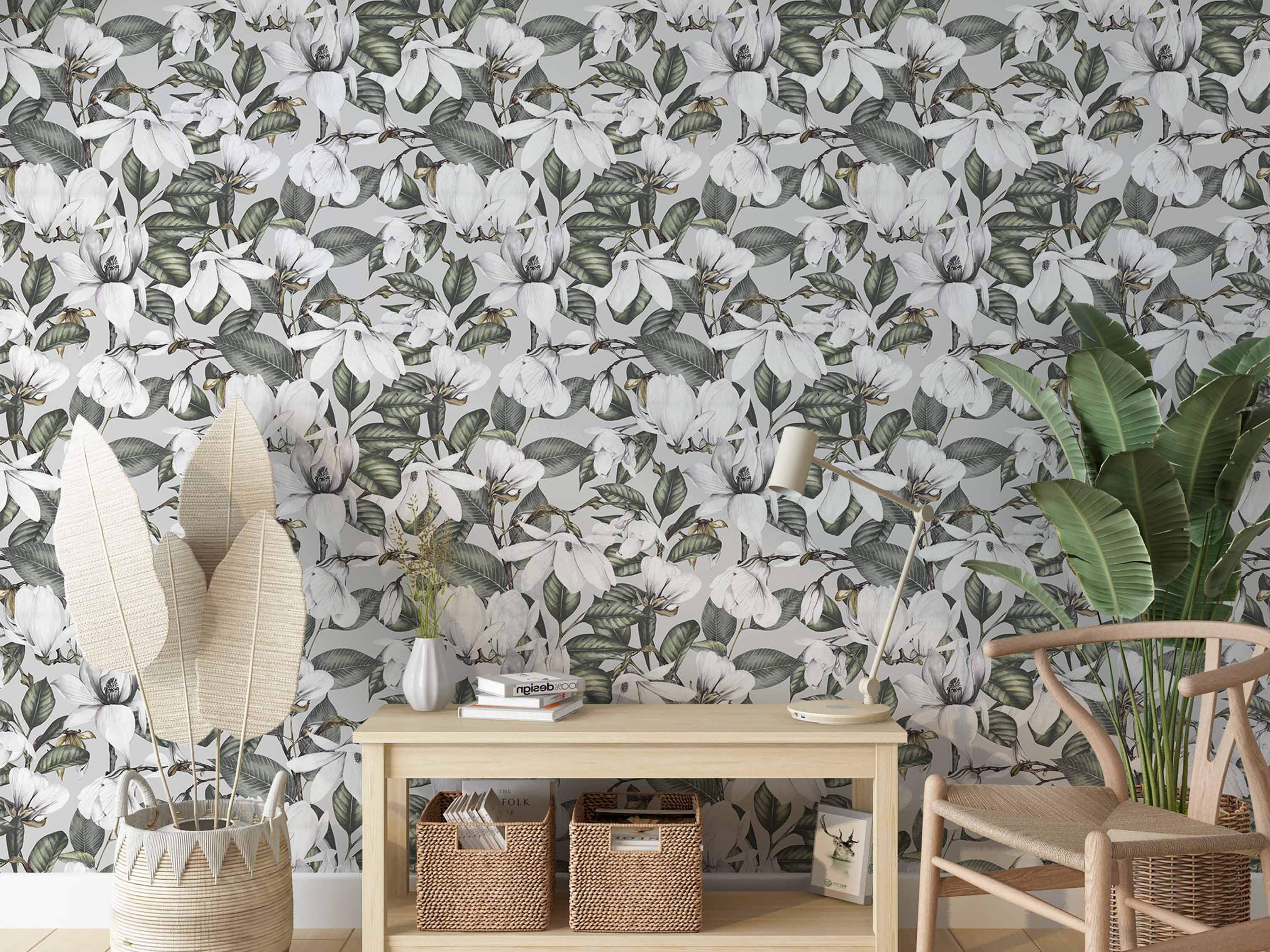 Wallpaper featuring detailed white magnolia blooms and lush green leaves scattered across a soft grey background.