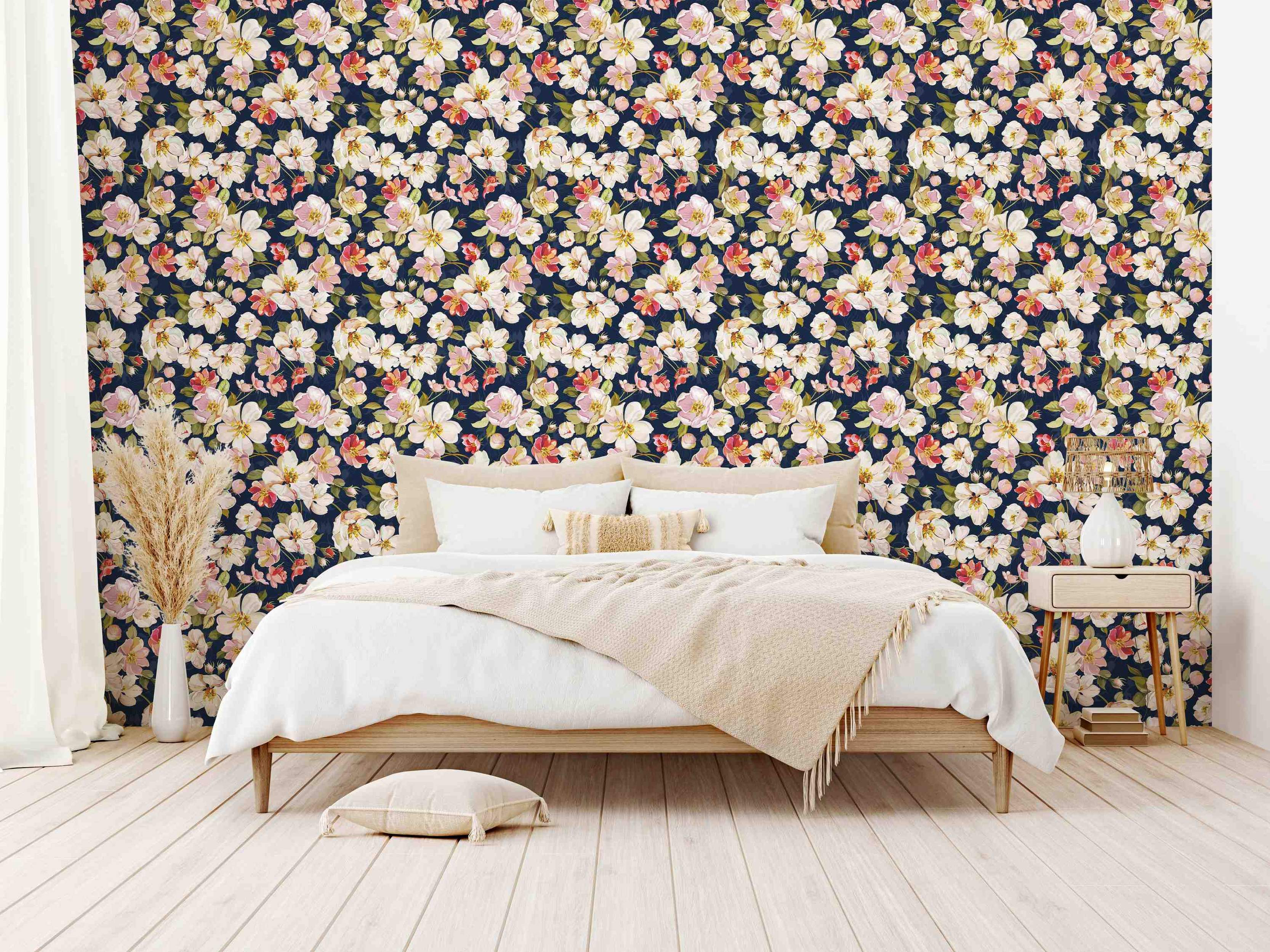 Wallpaper with a repeating pattern of painted pink, white, and cream flowers with green leaves against a dark navy blue background.