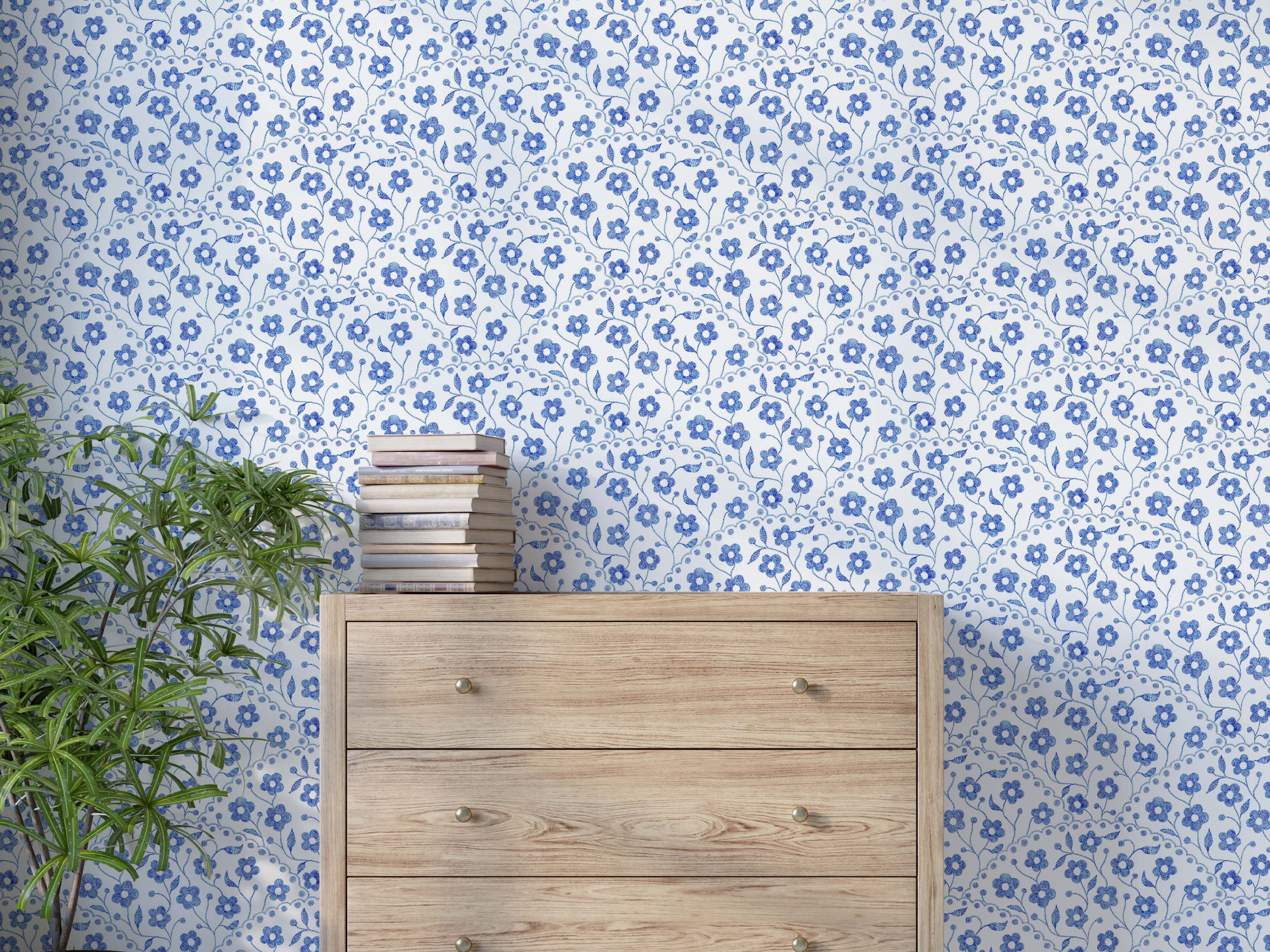 Wallpaper with a pattern of small blue flowers with a stitched texture, arranged in scalloped vertical stripes on a white field.