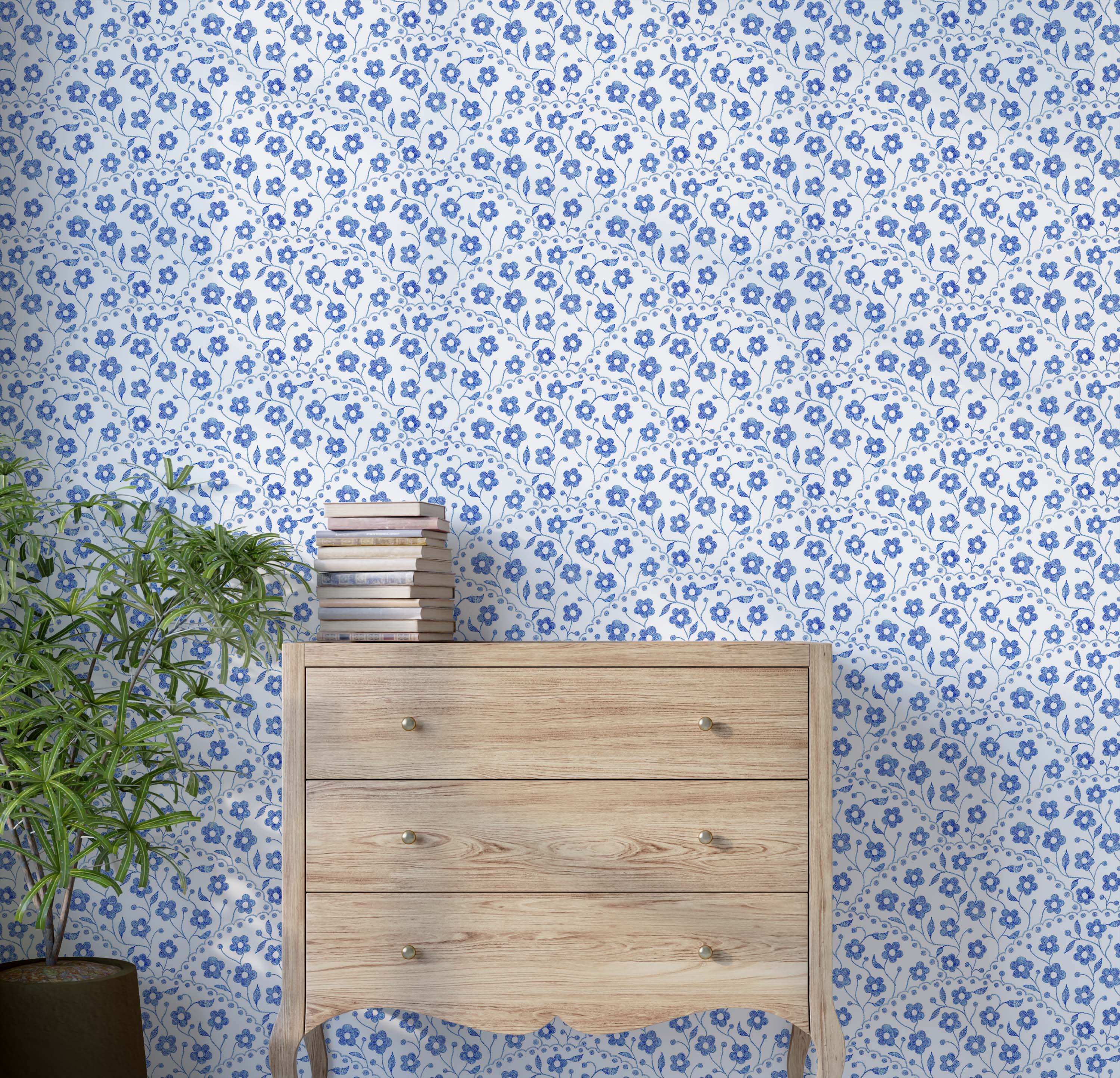 Wallpaper with a pattern of small blue flowers with a stitched texture, arranged in scalloped vertical stripes on a white field.