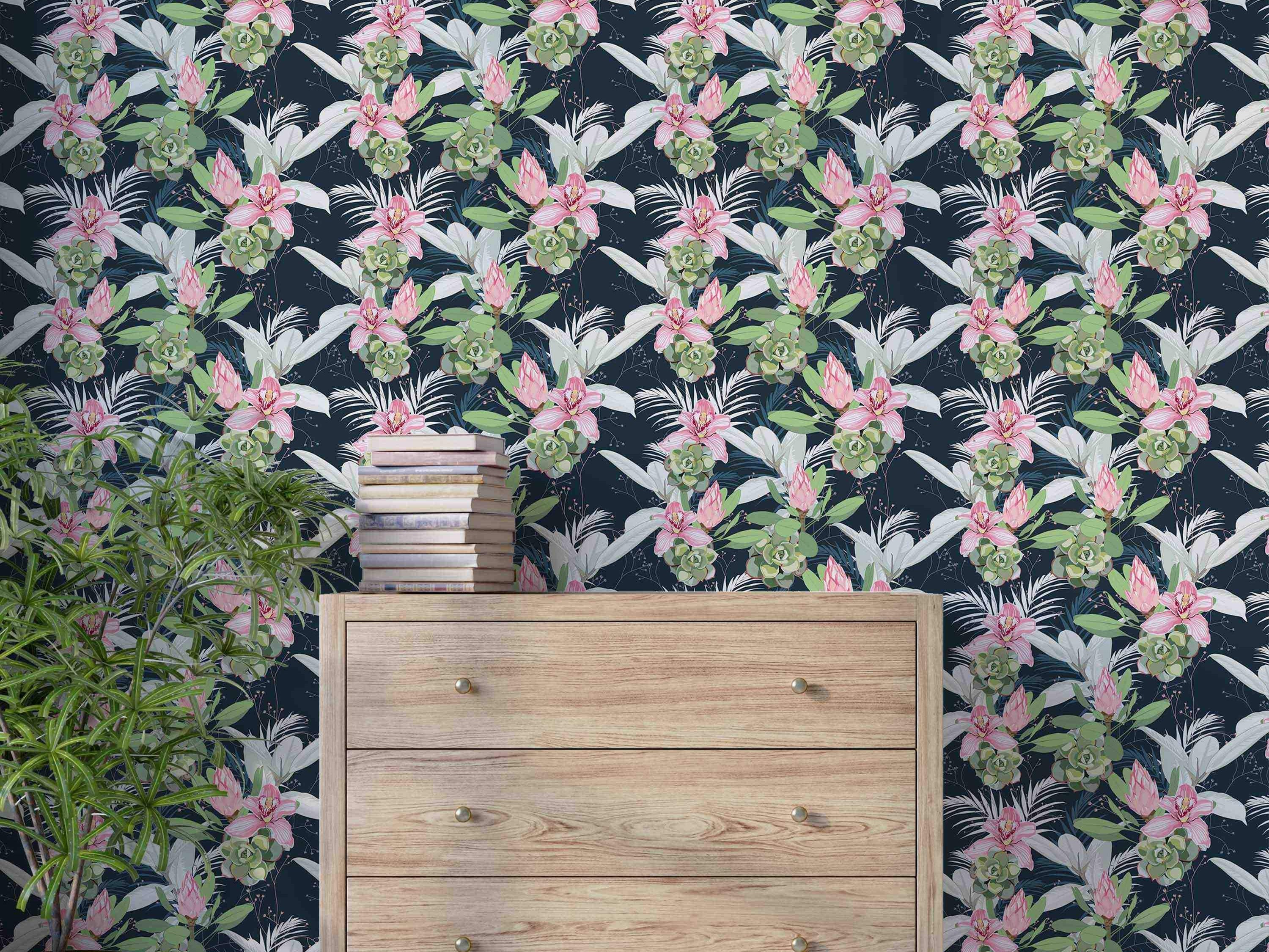 Botanical wallpaper with a repeating pattern of pink orchids, protea, green succulents, and white leaves on a dark blue field.