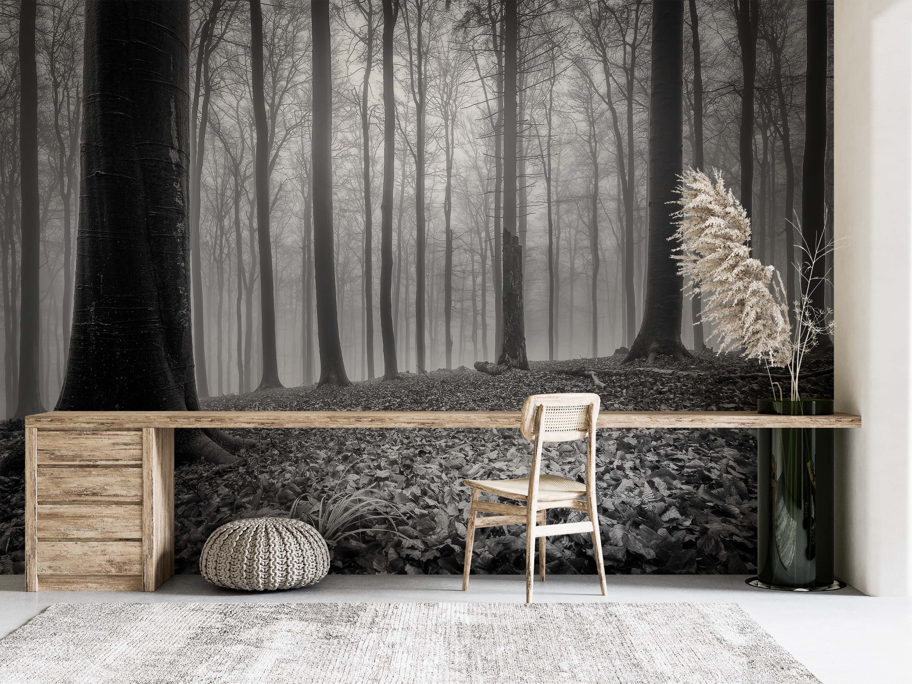 A moody black and white photo mural of a foggy forest with tall, bare trees and a leaf-covered ground.