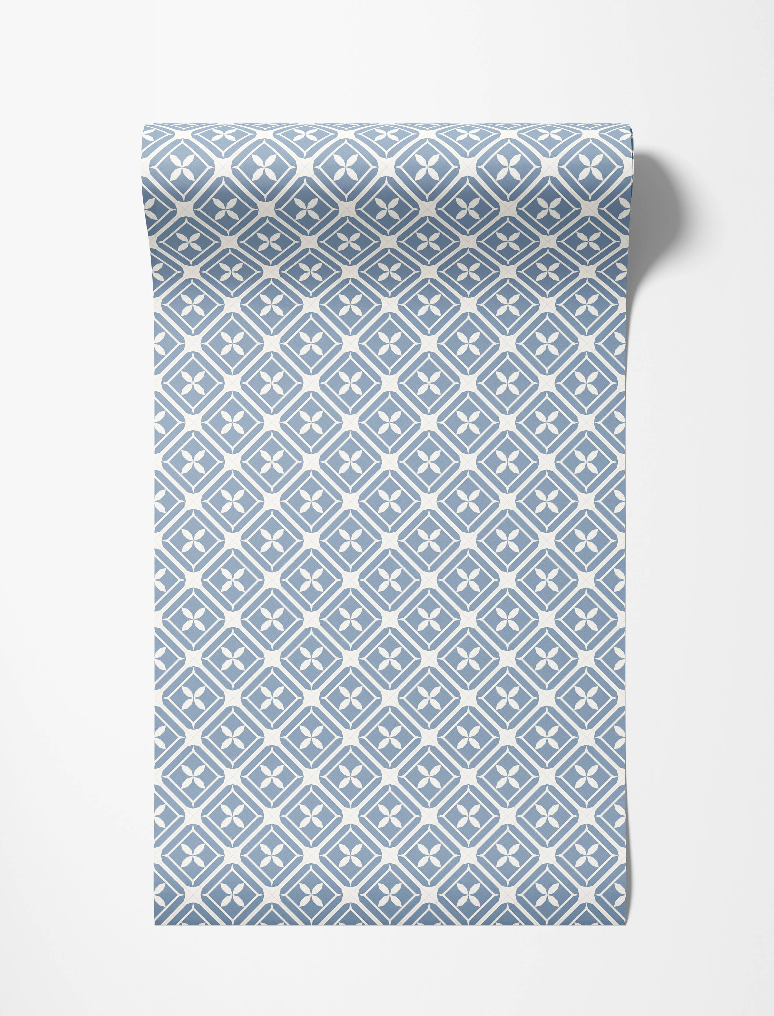 Dusty blue and off-white geometric wallpaper with a repeating pattern of diamonds enclosing four-petal flower designs.