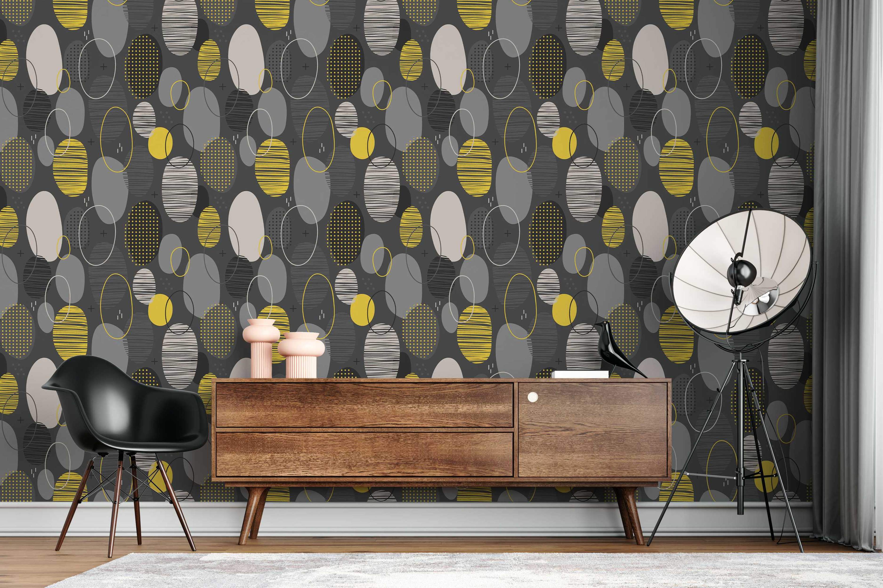 Geometric wallpaper featuring layered oval shapes in yellow, gray, and beige with line and dot patterns on a dark gray field.